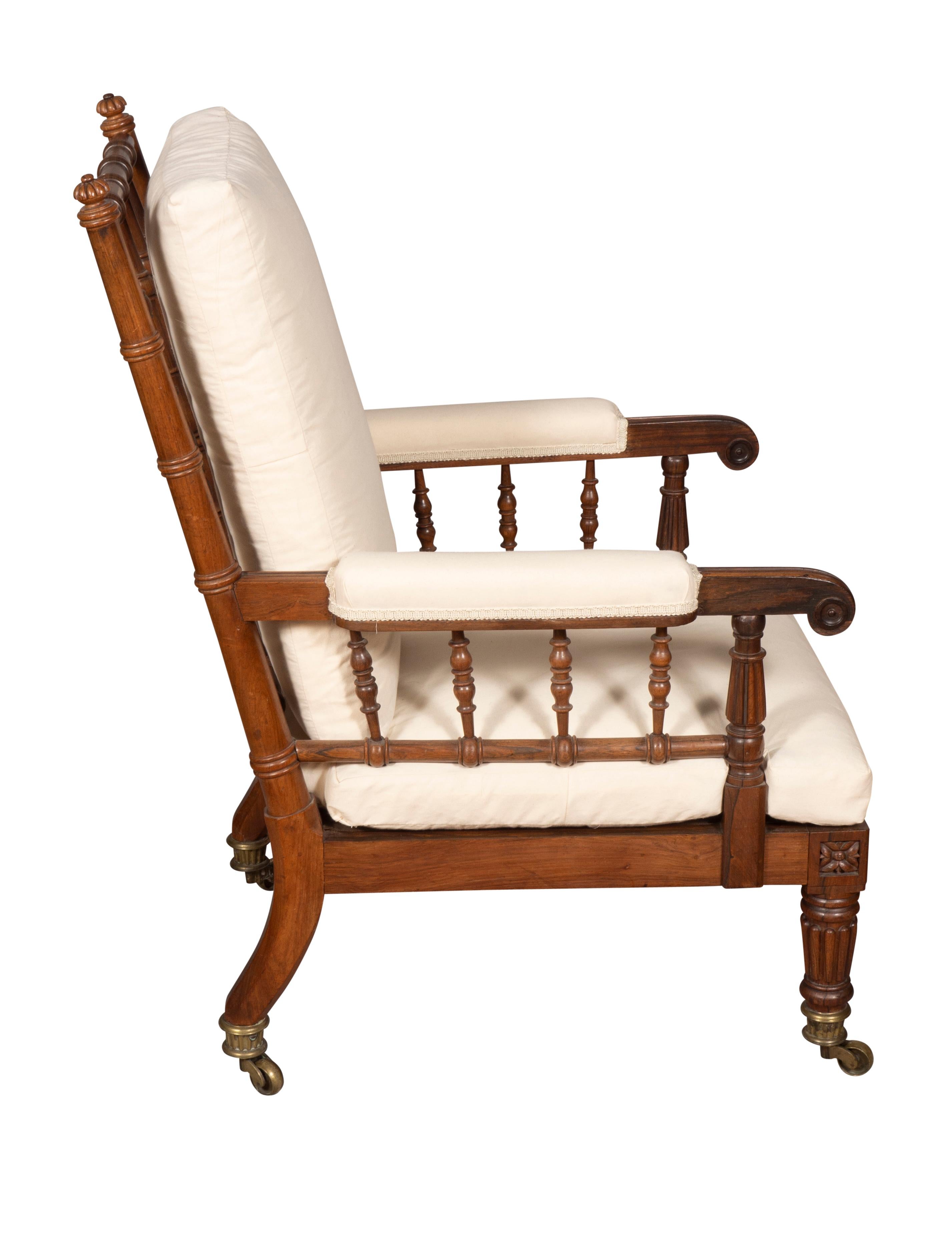 With rectangular back with spindles and loose muslin cushion, carved arms and loose cushion seat raised on circular reeded tapered legs and cup casters.