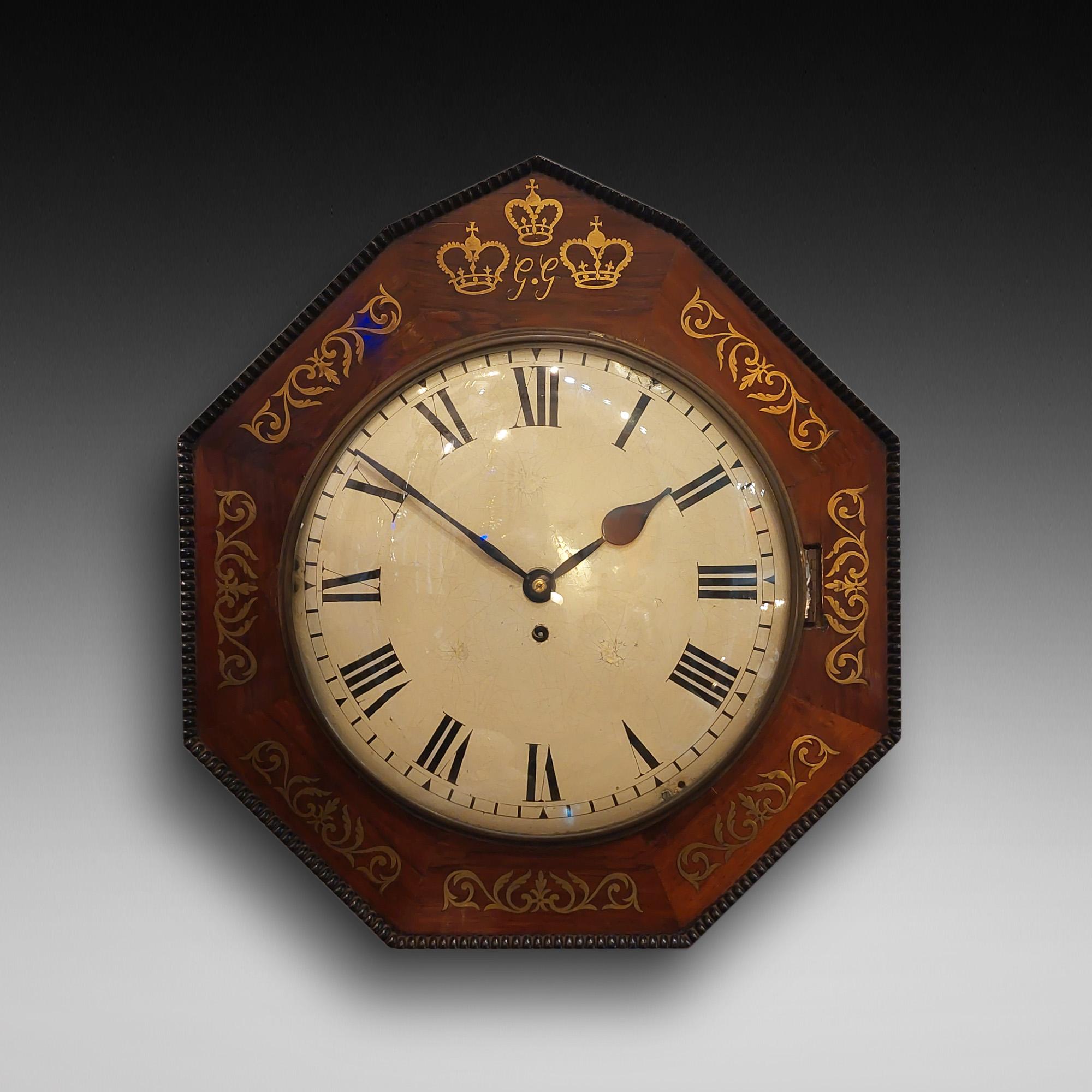 Regency rosewood and brass inlaid wall clock, the octagonal case brass inlaid with three crowns and monogrammed GG, over a convex white enamel Roman dial and single winding hole for a brass eight-day wire driven fusse movement, with pendulum - the