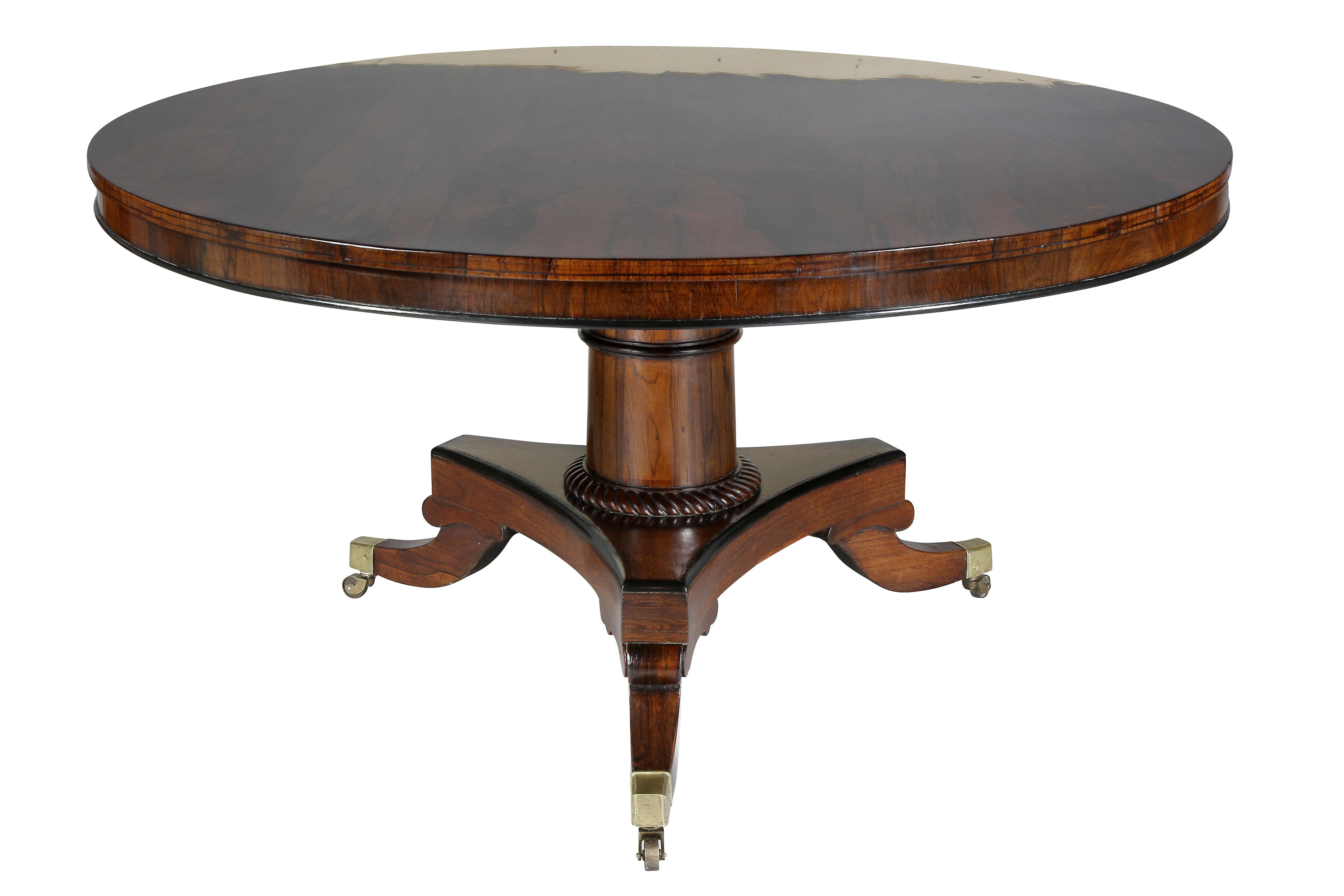 Round top with fabulous figure over a conforming apron, the turned support with rope carved base joining a tripartite base with three saber legs ending on casters. Brass latch signed Bullock. George Bullock was an accomplished cabinetmaker and