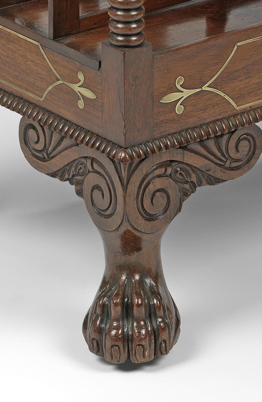 A very unusual and fine early 19th century rosewood Canterbury, having four bowed divisions with a central brass carrying handle, on four turned supports with brass finials above a brass inlaid frieze, the claw feet being surmounted by foliate and