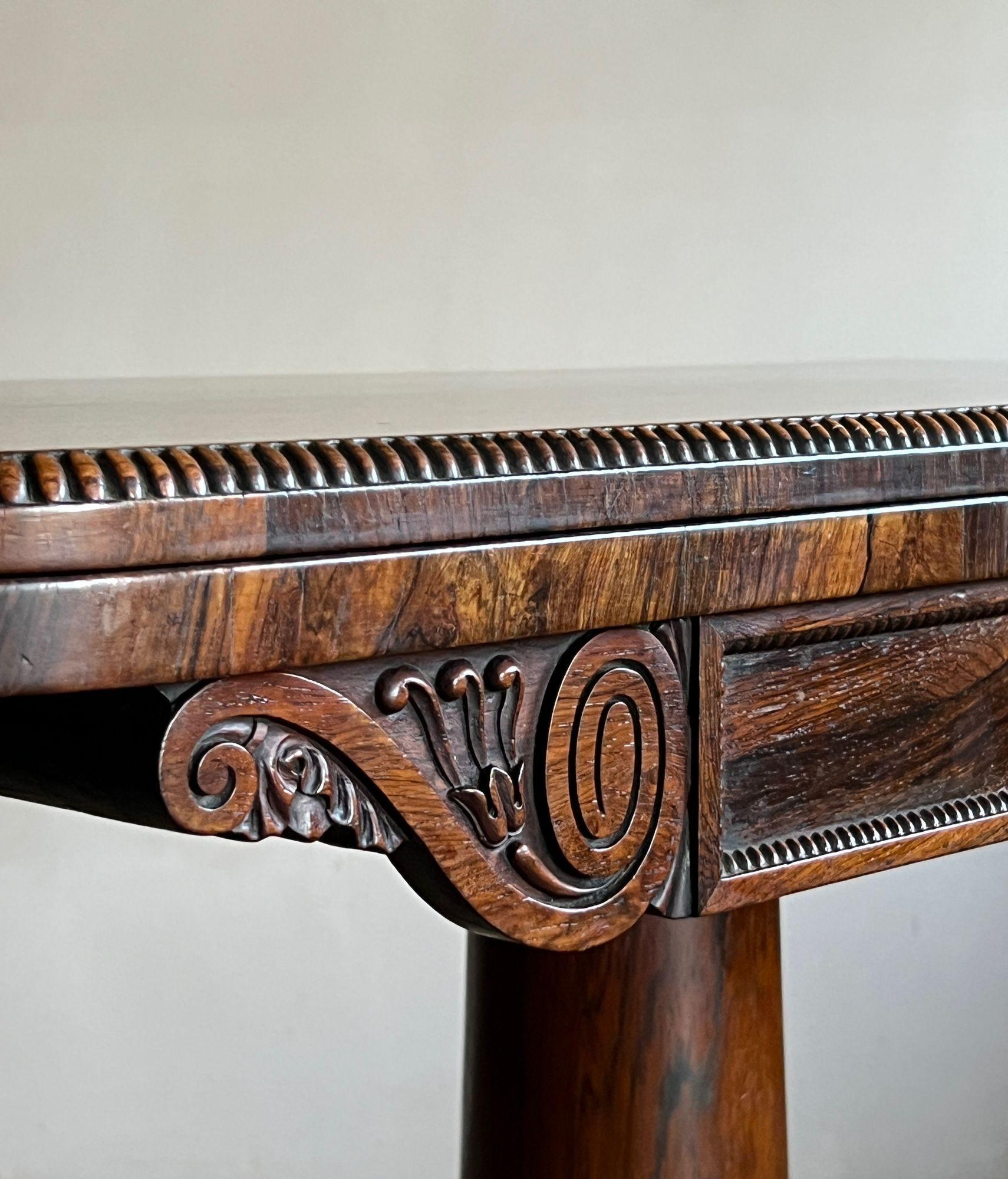 Table en palissandre de la fin de la Régence ou de la période Guillaume IV, avec un plateau rabattable et une surface en biseau pour les cartes/jeux. Avec un bois fin et dense, un bord et une frise en quadrant, flanqués de consoles sculptées en