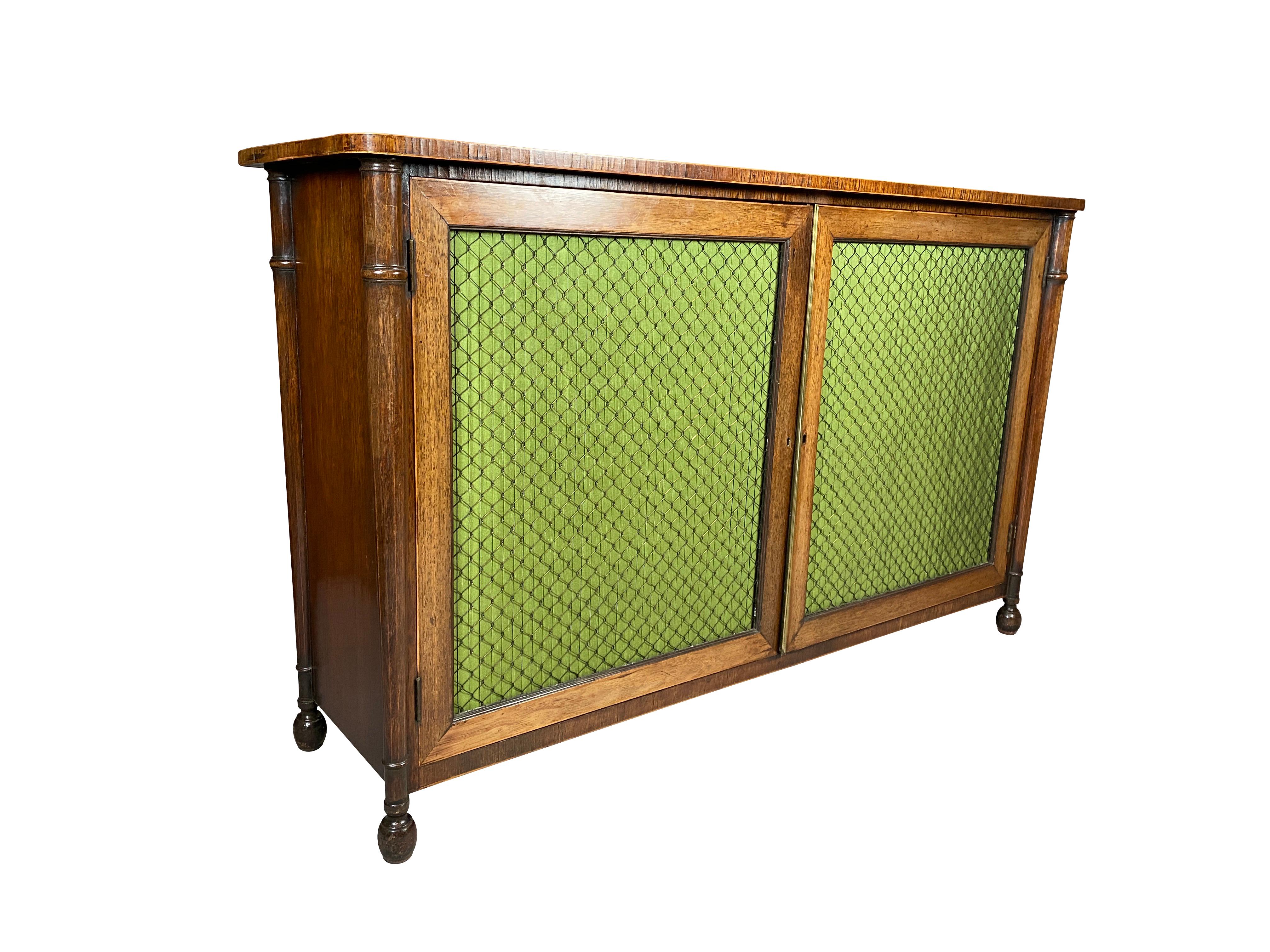 With rectangular cross banded top over a pair of wire and pleated green silk paneled doors enclosing two original shelves raised on turned feet.