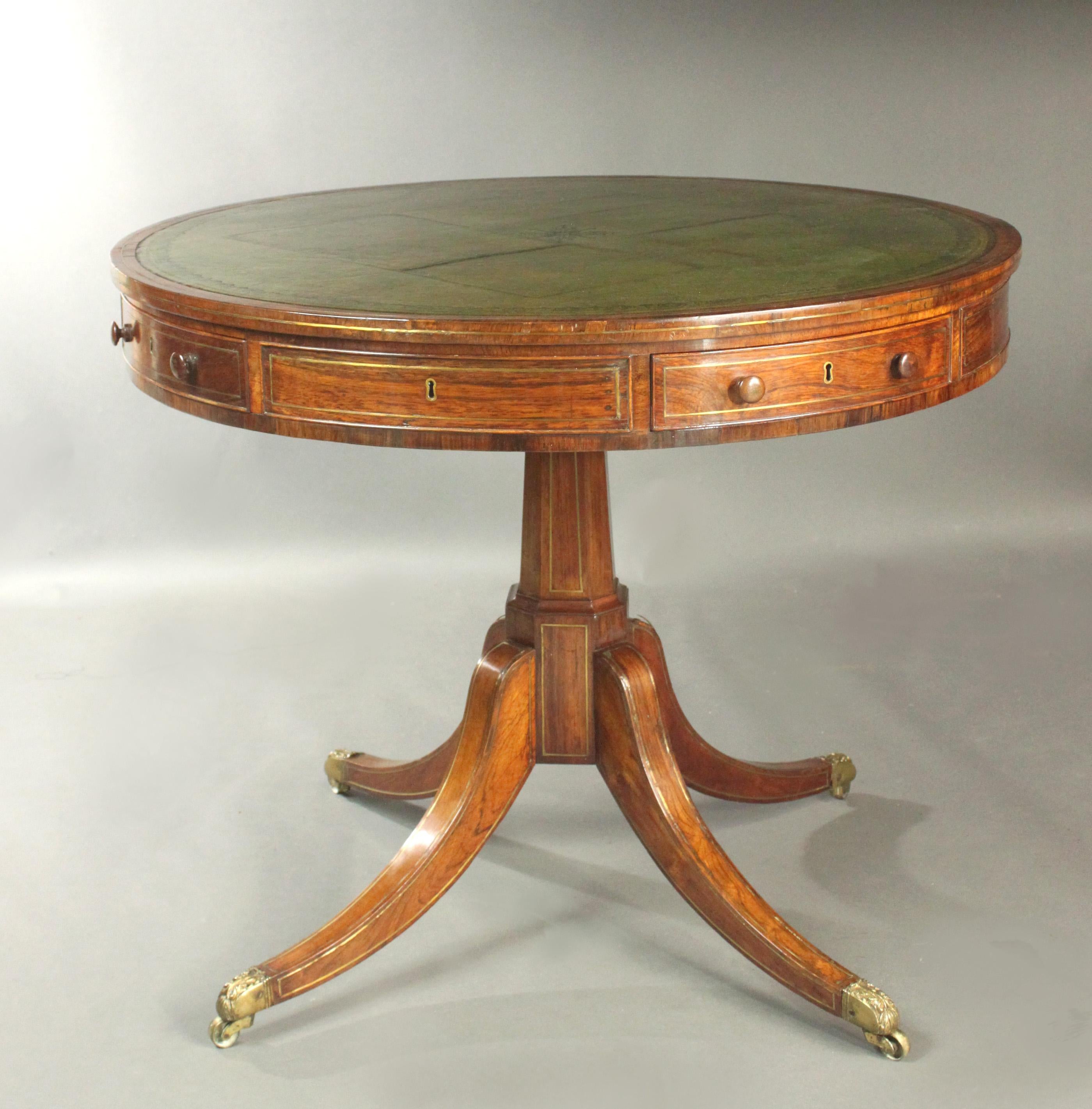 A fine quality Regency rosewood drum table with attractive brass stringing, good small size and original colour and patina. Handsome faceted column, sabre legs and cup castors with acanthus leaves which still retain their old lacquer finish. The top