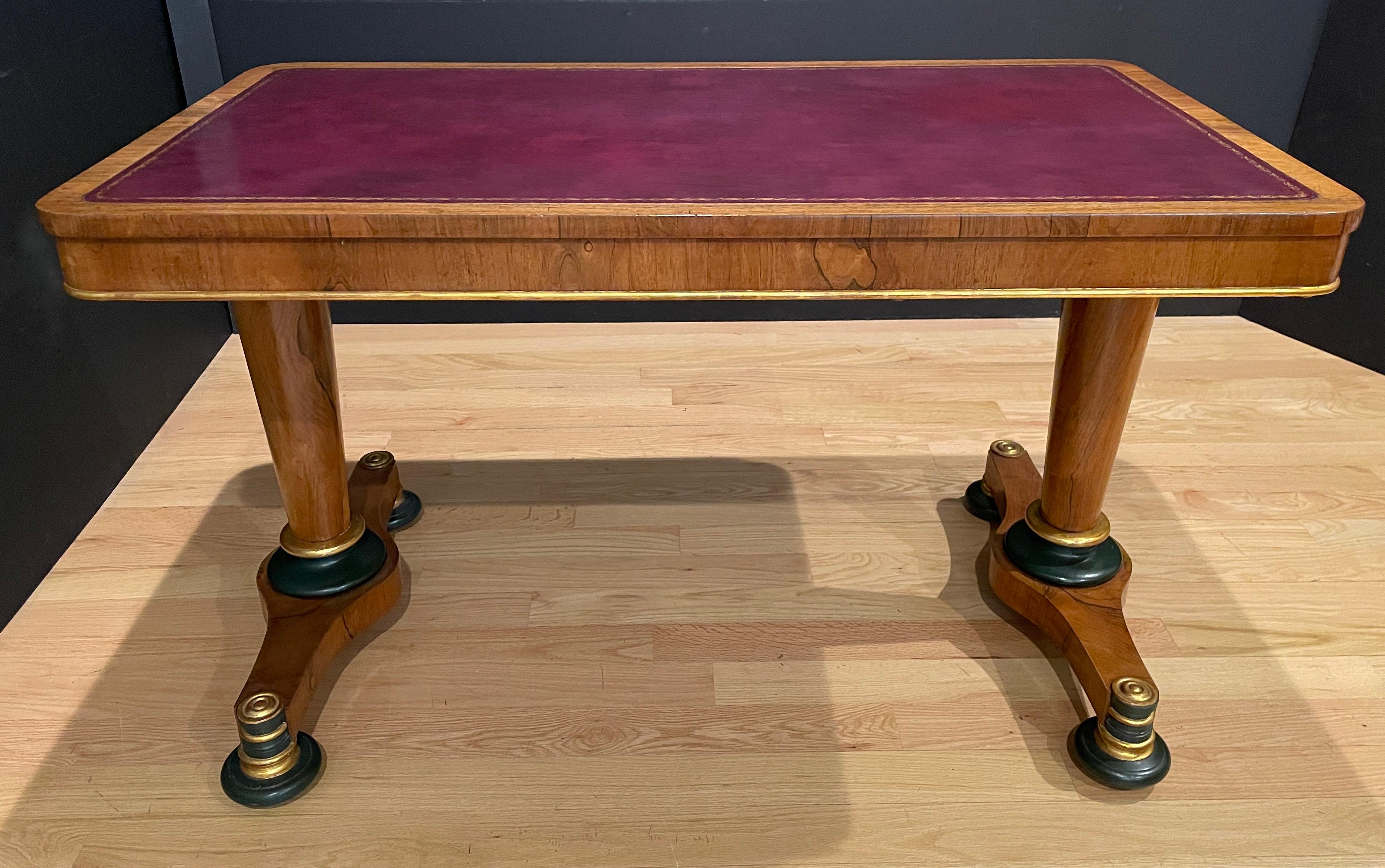 Fine quality tapered leg walnut, gilt and painted leather top library table. Burgundy tooled and gilt leather top. Tapered pedestal legs ending in small platform with gild details and bun feet.