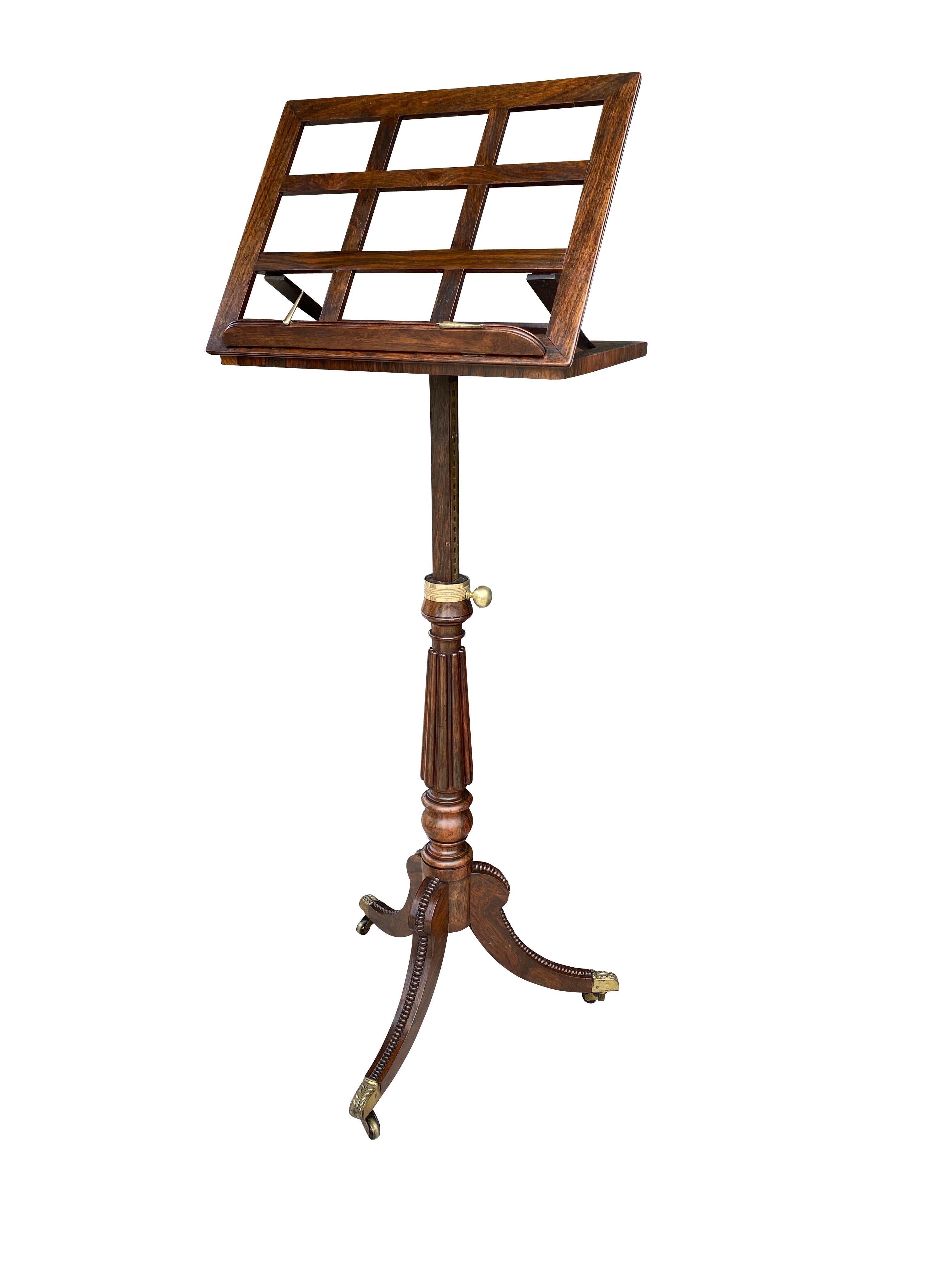 With hinged trellis adjustable holder and hinged folding book rest raised on a reeded support headed by a brass knob to adjust height, raised on three saber legs with cup casters. Likely by Gillow.