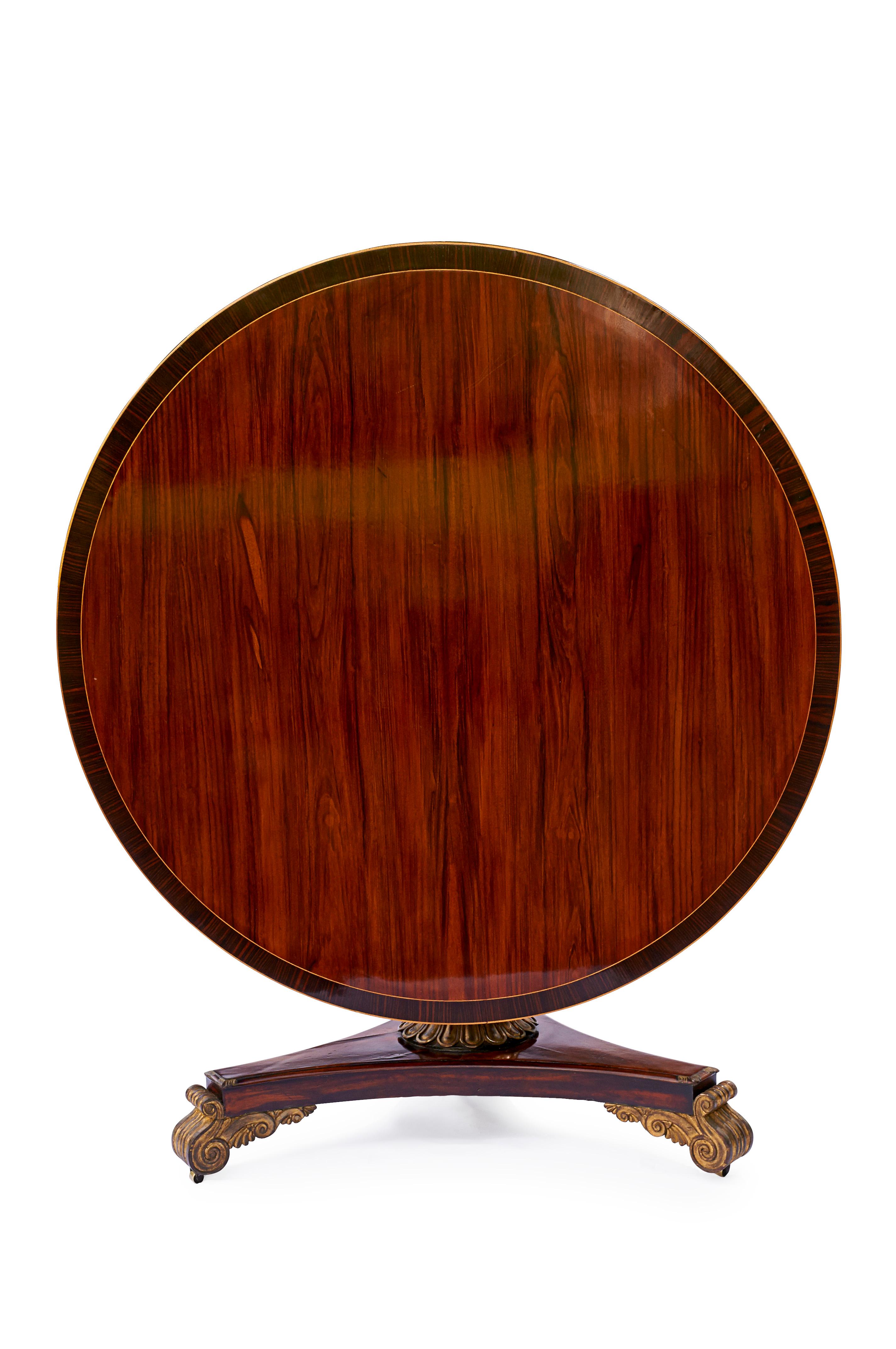 A stunning Regency parcel gilt rosewood and mahogany breakfast or hall table, in excellent quality. 

The circular line inlaid has a cross-banded top above a gilt bead, with reel-banded recessed frieze, raised on three water reed-banded columnar