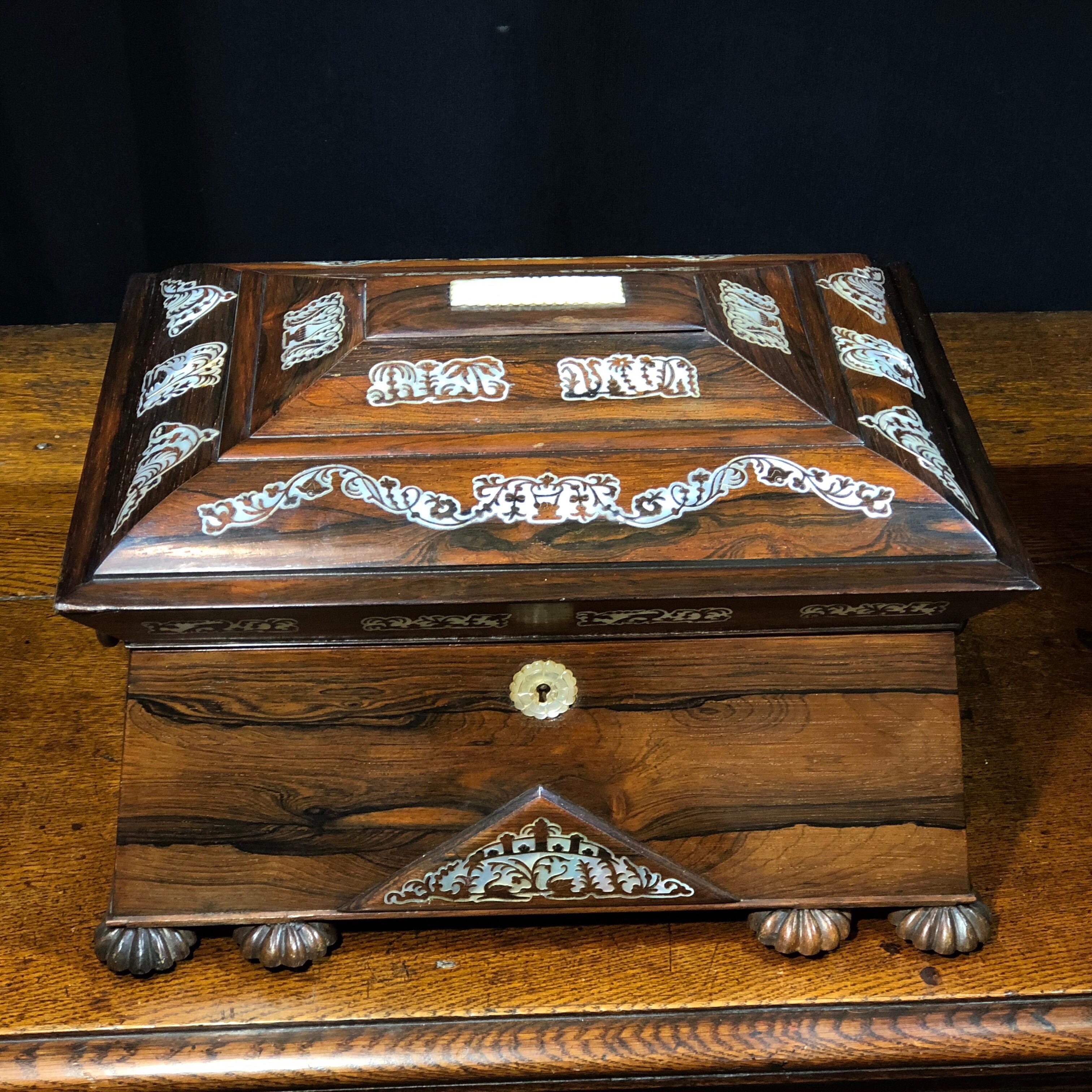 William IV rosewood sarcophagus form sewing box, the domed lid with inlaid panels in mother of pearl including swans, the interior with original crimson silk compartments containing carved pearl spools etc., the lid containing concealed musical