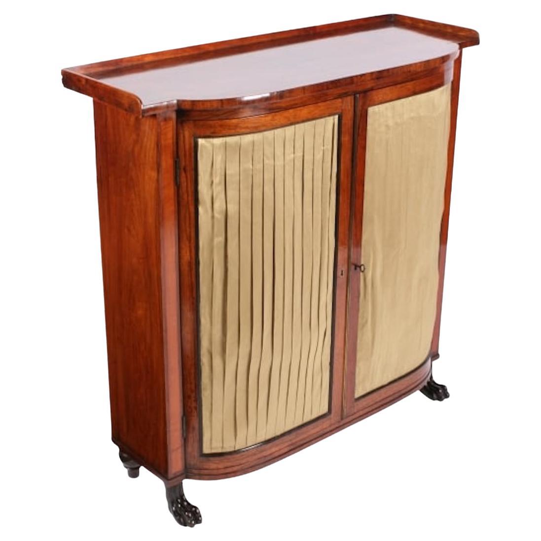 Regency rosewood side cabinet

An early 19th century Regency rosewood side cabinet.

The two door bow fronted cabinet stands on four carved paw feet.

The pair of doors have pleated silk covered centre panels with an ebony bead inner edge and