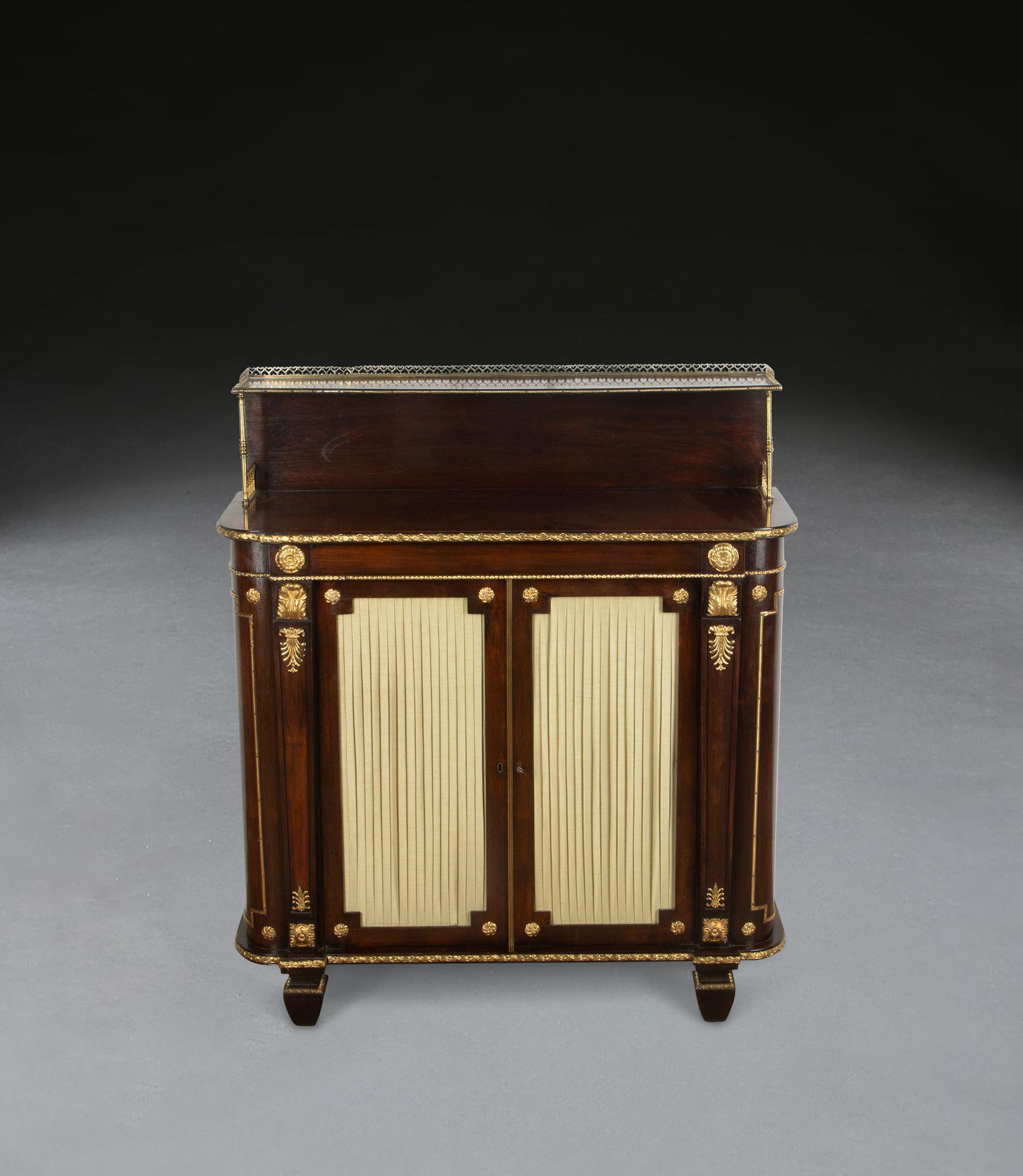 A Regency rosewood and ormolu mounted side cabinet, the shelf with brass gallery and slender supports, above a well figured top with ormolu moulding and shaped sides behind tapering pilasters with further ormolu rosettes, acanthus and anthemions