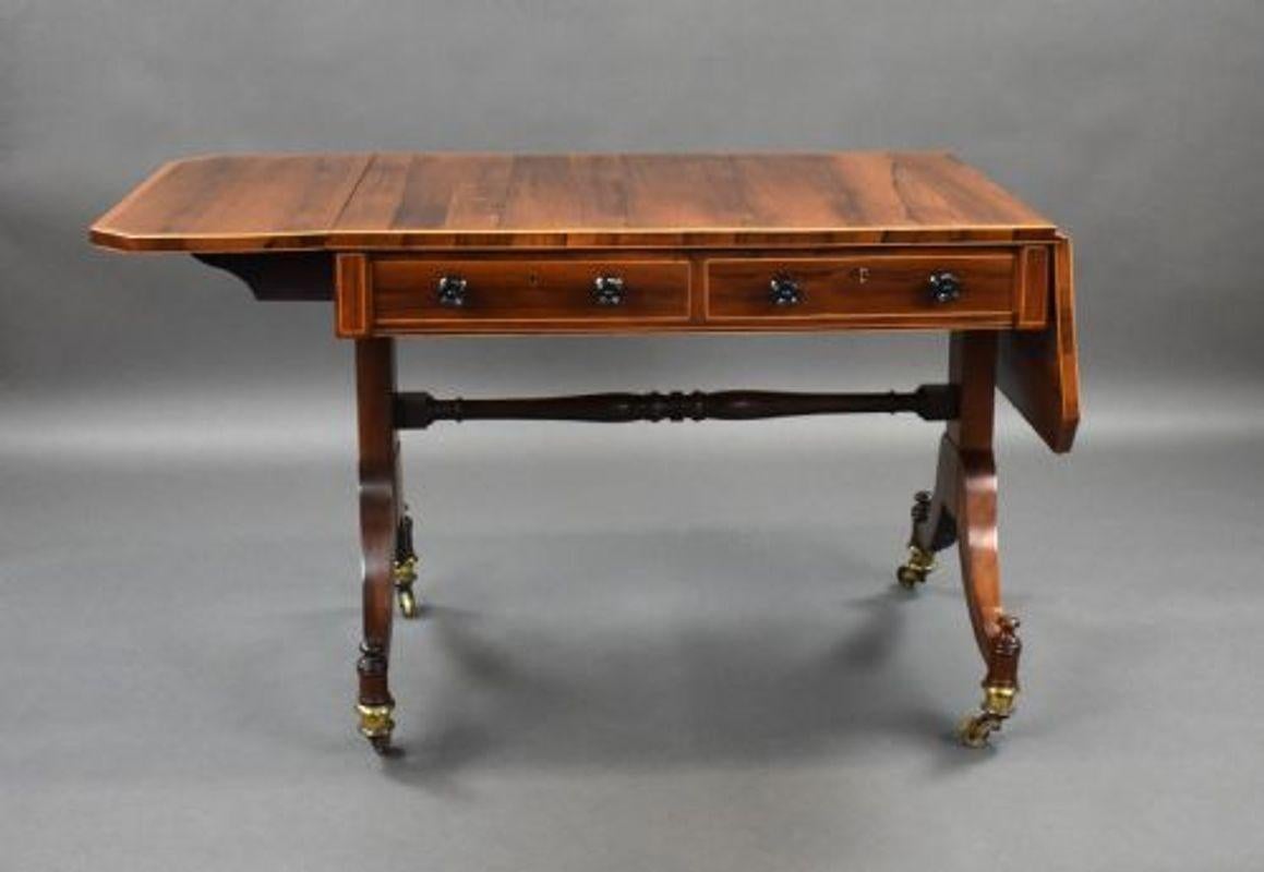 For sale is a good quality Regency rosewood sofa table, the rosewood top with banded edge and two drop leaves, with a central stretcher uniting two legs raised on brass castors. This piece is in very good condition, showing minor wear commensurate