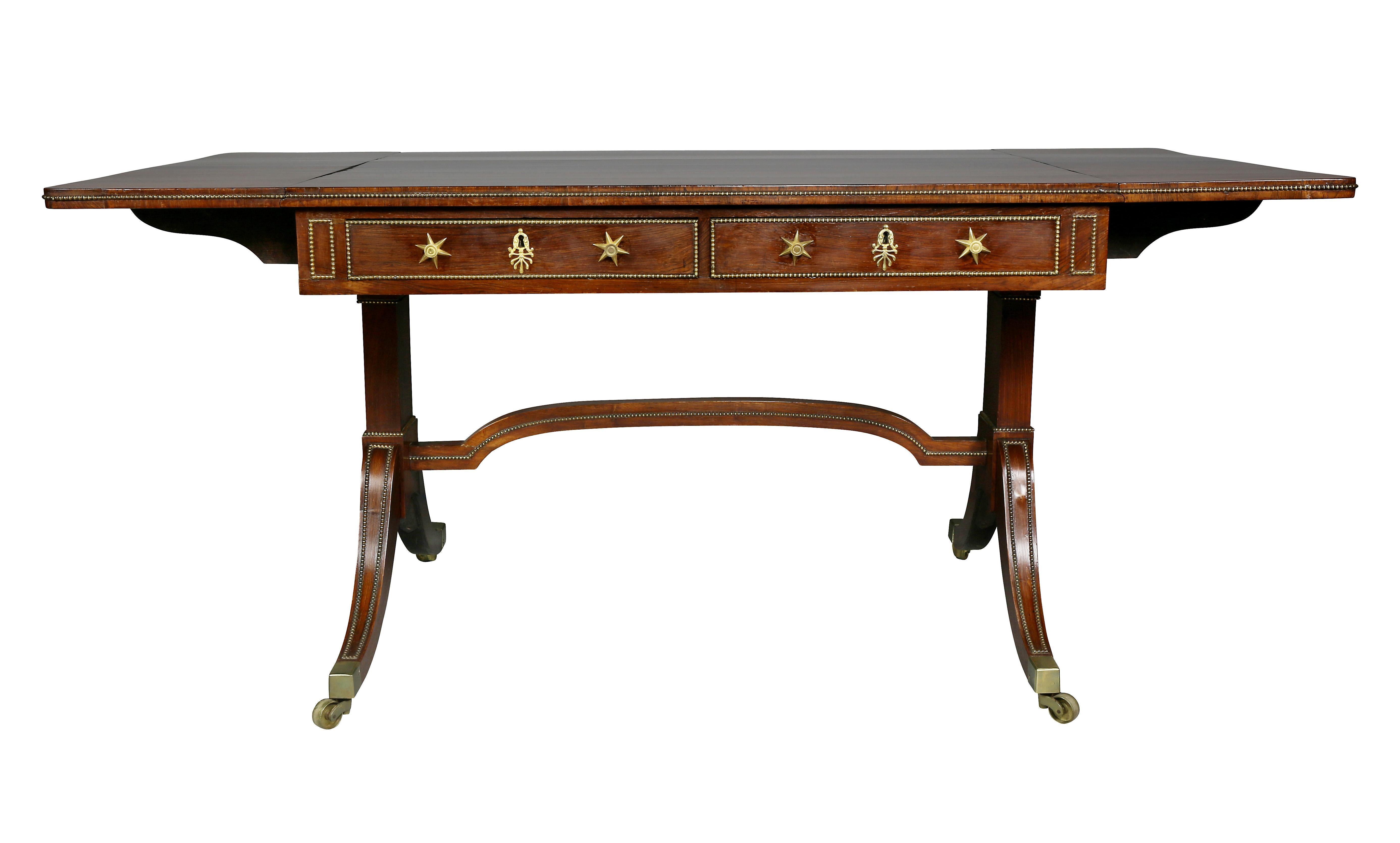 Rectangular with drop leaves, metal beaded edge, two-drawer frieze with opposing sham drawers, raised on trestle base, saber legs, casters.