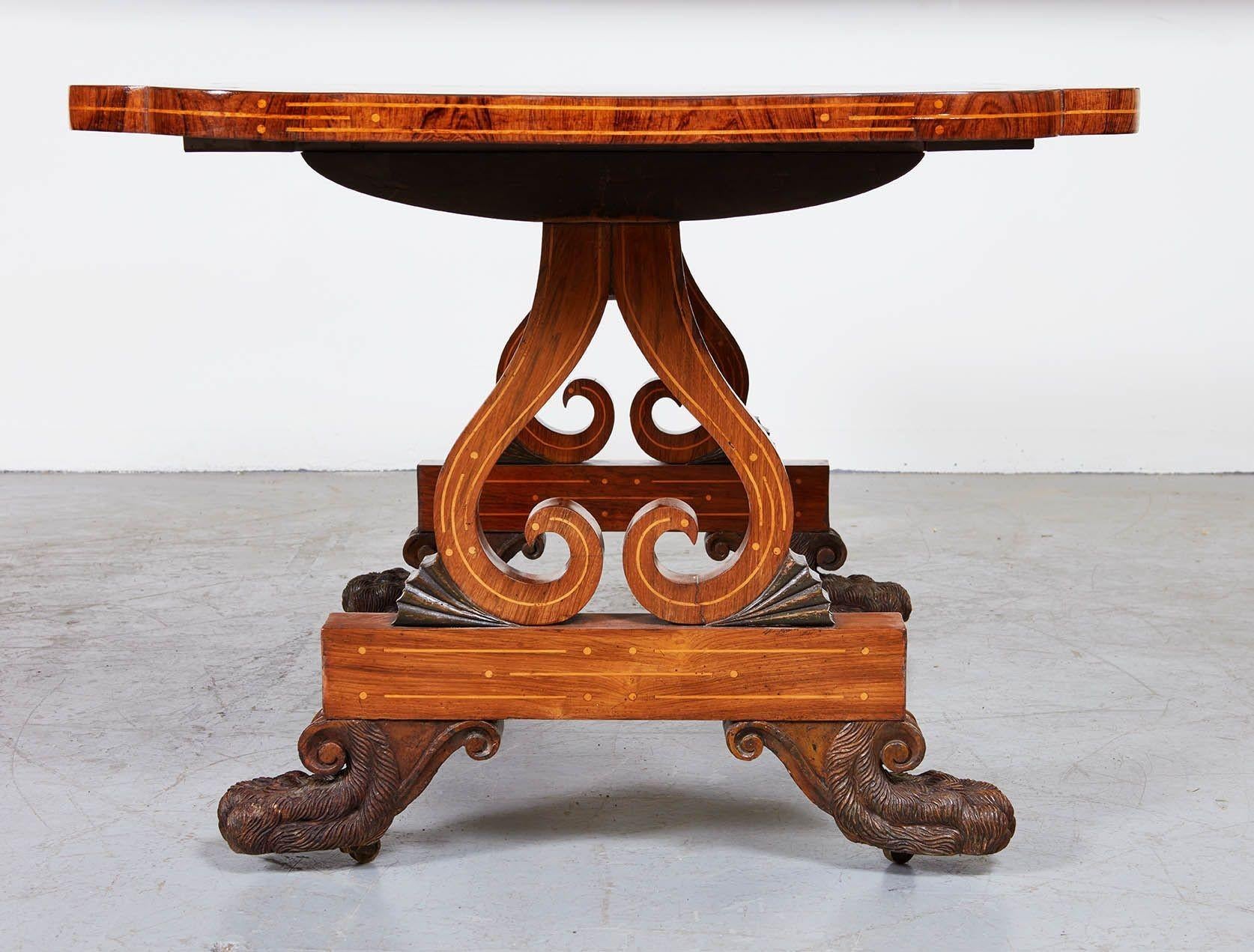 Fine Regency period rosewood library or writing table, the lobed top with satinwood banding and inlaid edge, over lyre base similarly inlaid and standing on boldly carved hairy lion paw feet, in the manner of George Oakley. Rich timber and