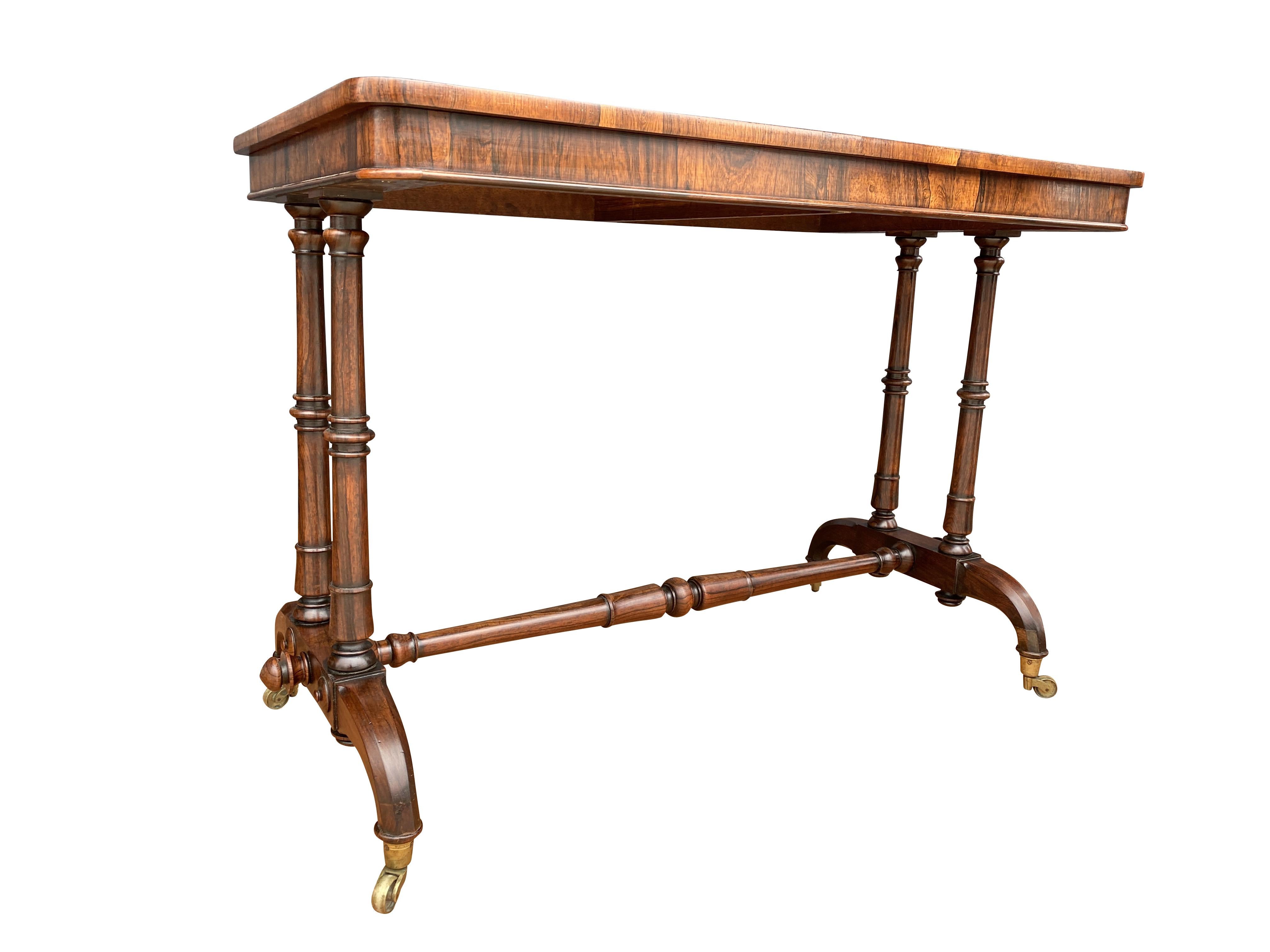 Rectangular top with rounded corners and conforming frieze, raised on turned legs joined by a turned stretcher, carved shaped legs and casters.