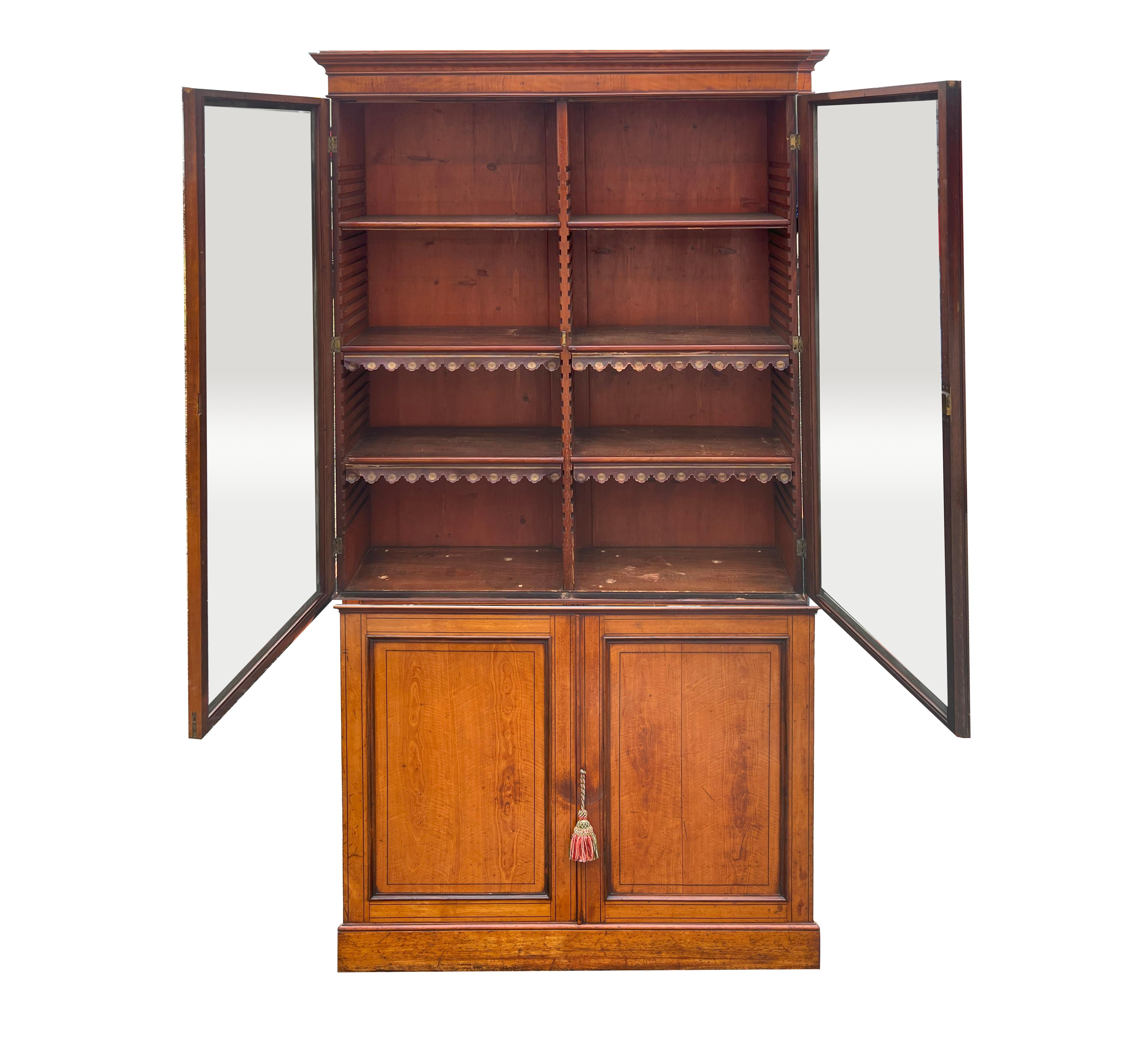 With rectangular shaped cornice over a pair of glass doors enclosing three shelves. The lower section with a pair of cabinet doors enclosing two shelves. Plinth base. With Key.