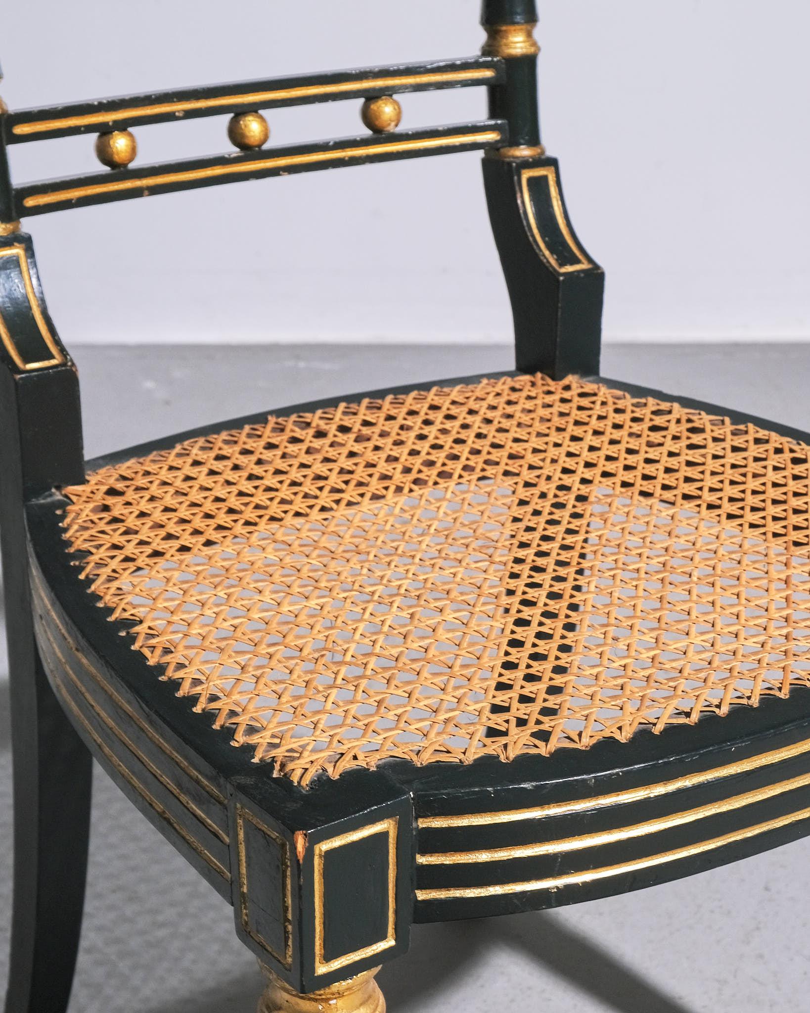 Une chaise d'appoint de style Regency anglaise magnifiquement travaillée, datant probablement du début du 19e siècle. Cette chaise présente un cadre remarquable peint en noir avec d'élégants accents dorés, soulignant le design néoclassique populaire