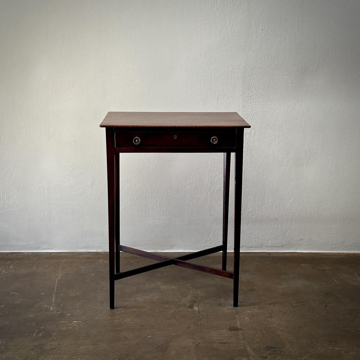 Cette table de lecture de l'époque Regency se distingue par ses longs pieds délicats et sa menuiserie en forme de X, offrant à la fois stabilité et style. Son tiroir est doté d'élégantes poignées en laiton, mettant en valeur sa silhouette élancée et