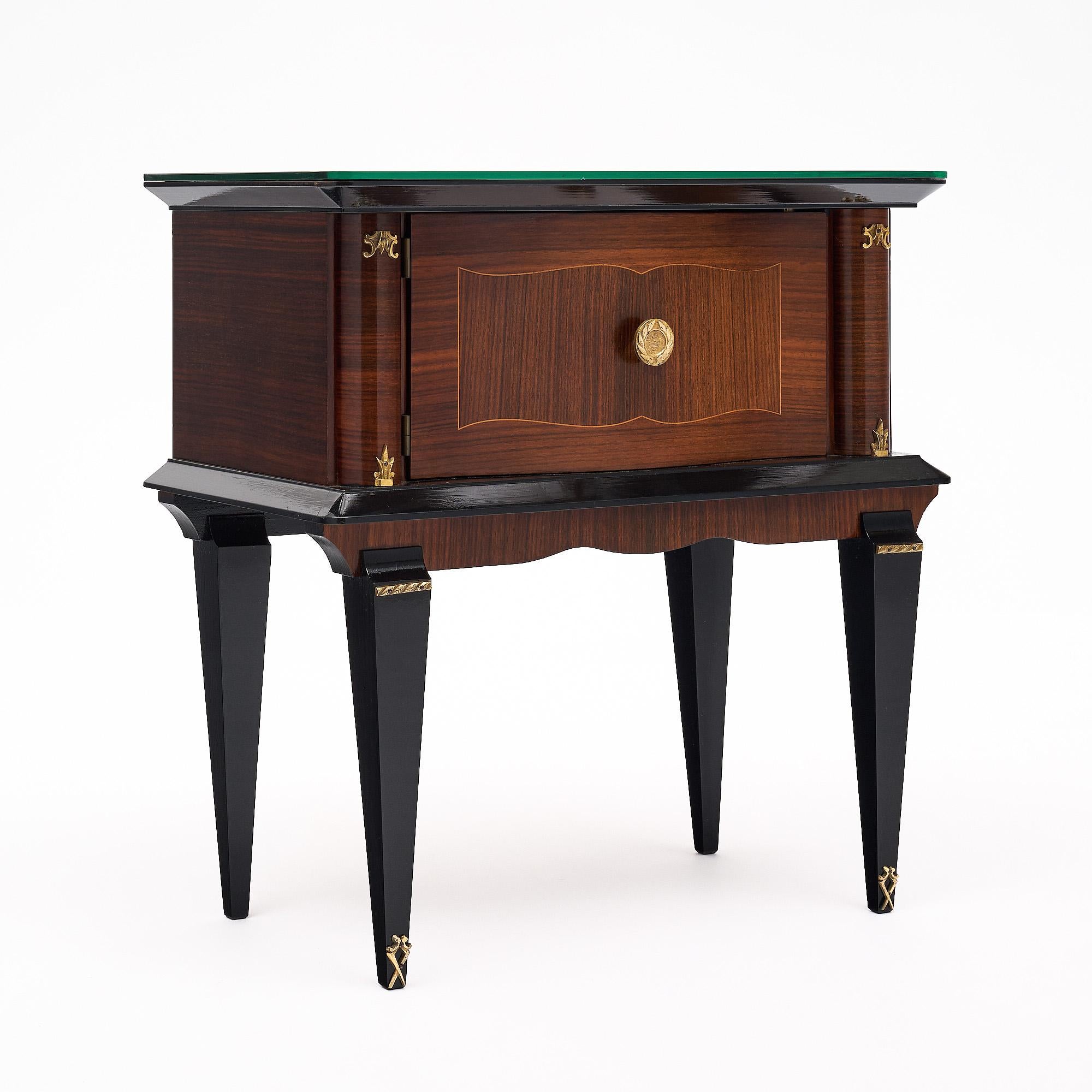 Paire de tables d'appoint en acajou, finition lustrée à la française avec accents ébonisés. Pieds fuselés avec accents en laiton doré et plateaux en verre miroir. Cette paire est en très bon état et ne présente qu'une usure superficielle mineure due
