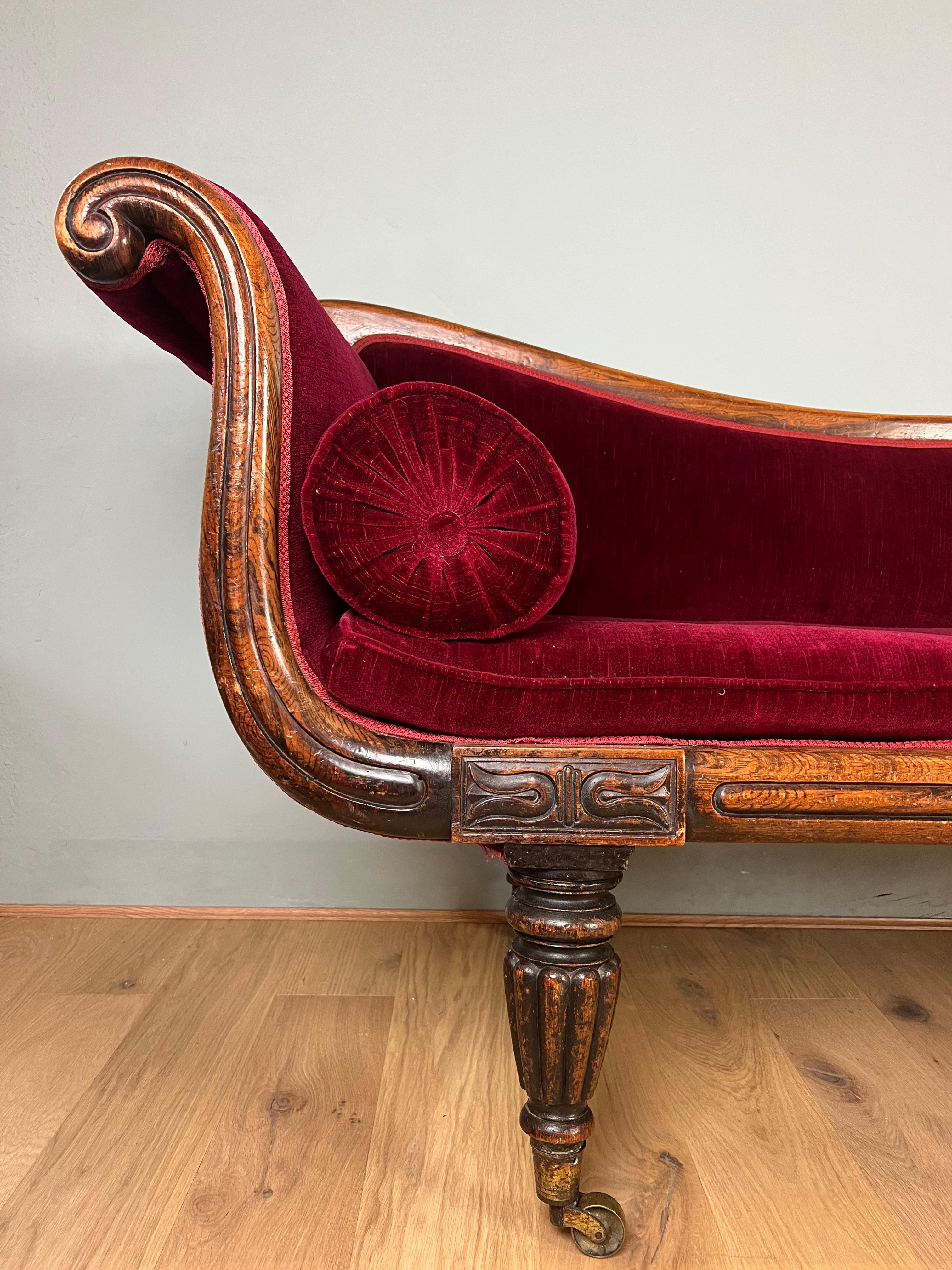 A very attractive Regency simulated rosewood (on beech) chaise-longue, elegantly shaped with a scroll back and side. Acanthus leaf decoration adorns the frieze, this rests on bold turned reeded legs and brass casters. This graceful chaise has claret
