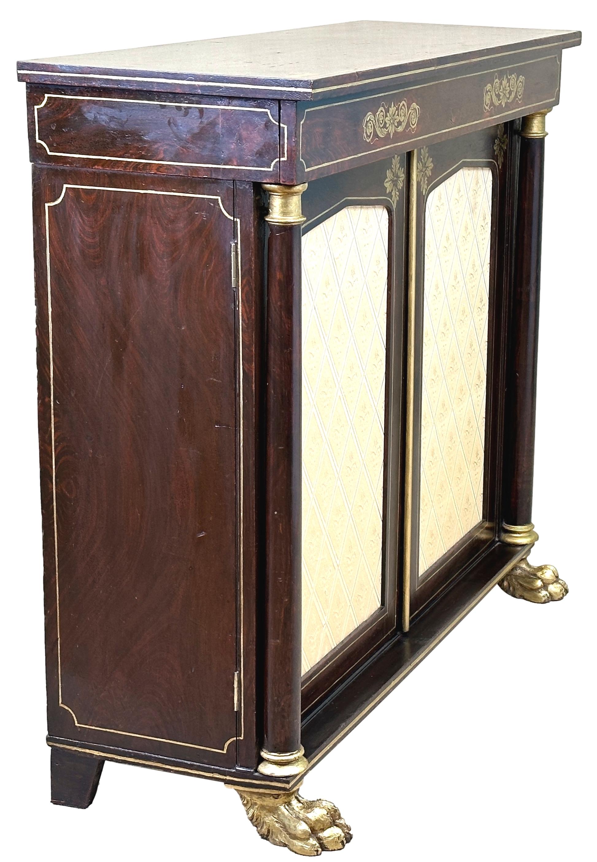 An Extremely Attractive Early 19th Century, Regency Period, Simulated Rosewood Side Cabinet, Having Elegant Parcel Gilt Decoration Throughout, The One Long Drawer Over Two Upholstered Panel Doors Flanked By Turned Columns, Raised On Fabulous