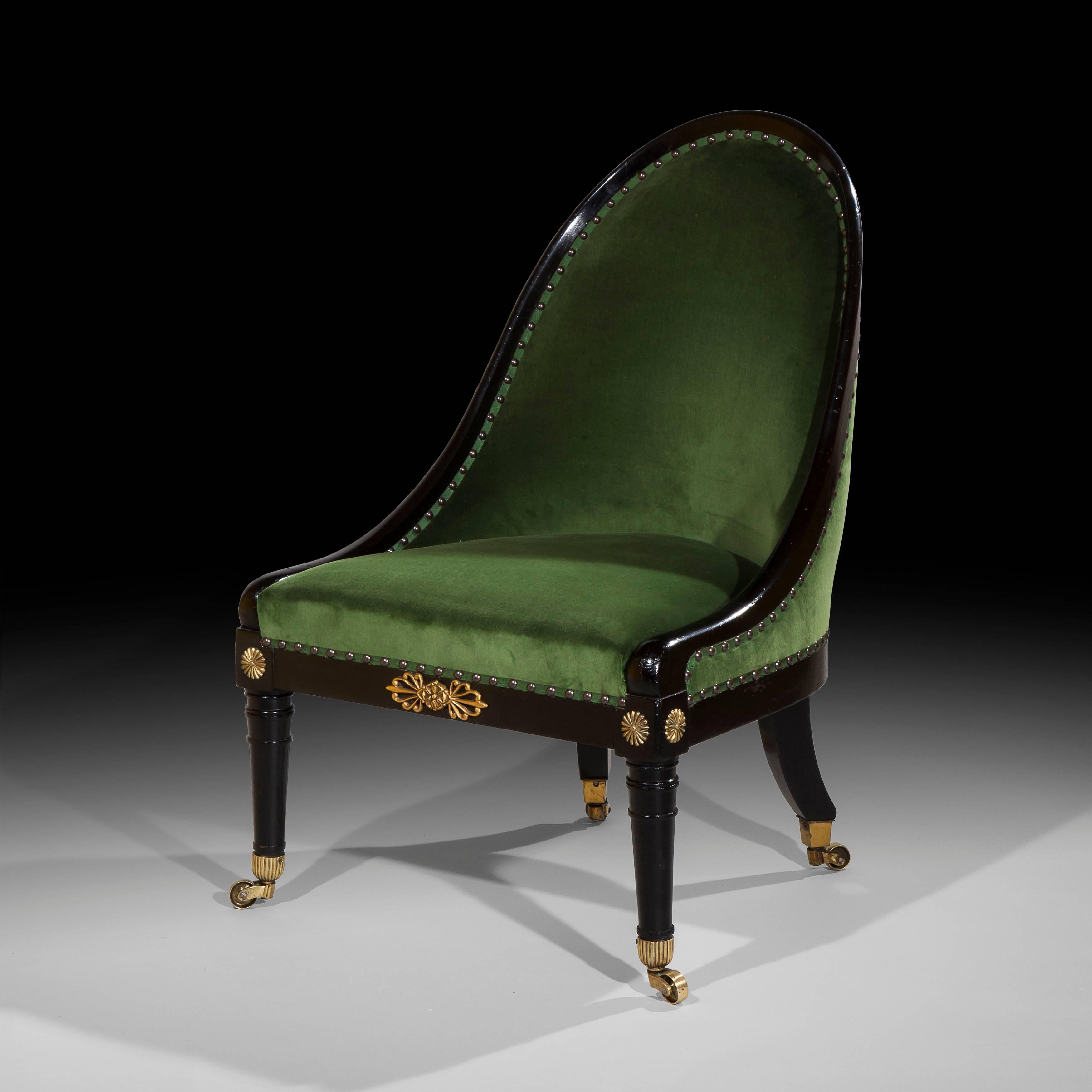 An elegant Regency period ebonised and brass mounted 'Roman' spoon-back low or slipper chair, circa 1810.

The padded arched spoon back over upholstered seat with brass embellished seat rails, raised on turned tapering supports at the front and
