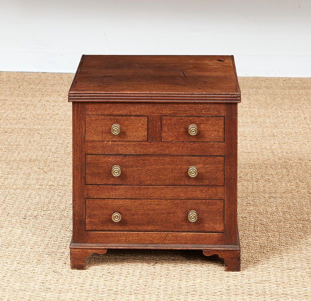 Une boîte de tabouret Regency bien construite avec un dessus à bord cannelé sur quatre faux tiroirs avec des boutons en laiton tourné reposant sur une plinthe à bord mouluré et des pieds en forme d'équerre.  La partie supérieure s'ouvre pour le