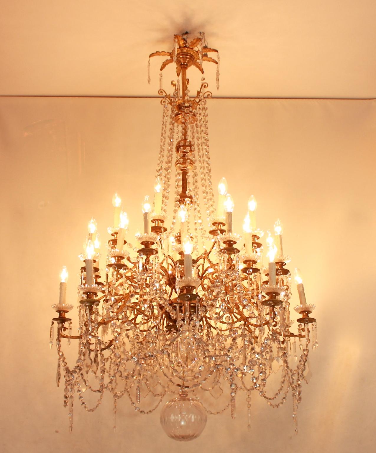 Monumental Regence-style thirty-six light gilt bronze and crystal-cut chandelier from circa 1860. The massive central baluster stem finely cast with mascarons, arabesque ornament and acanthus leaves, issuing thirty six scrolling foliate candlearms