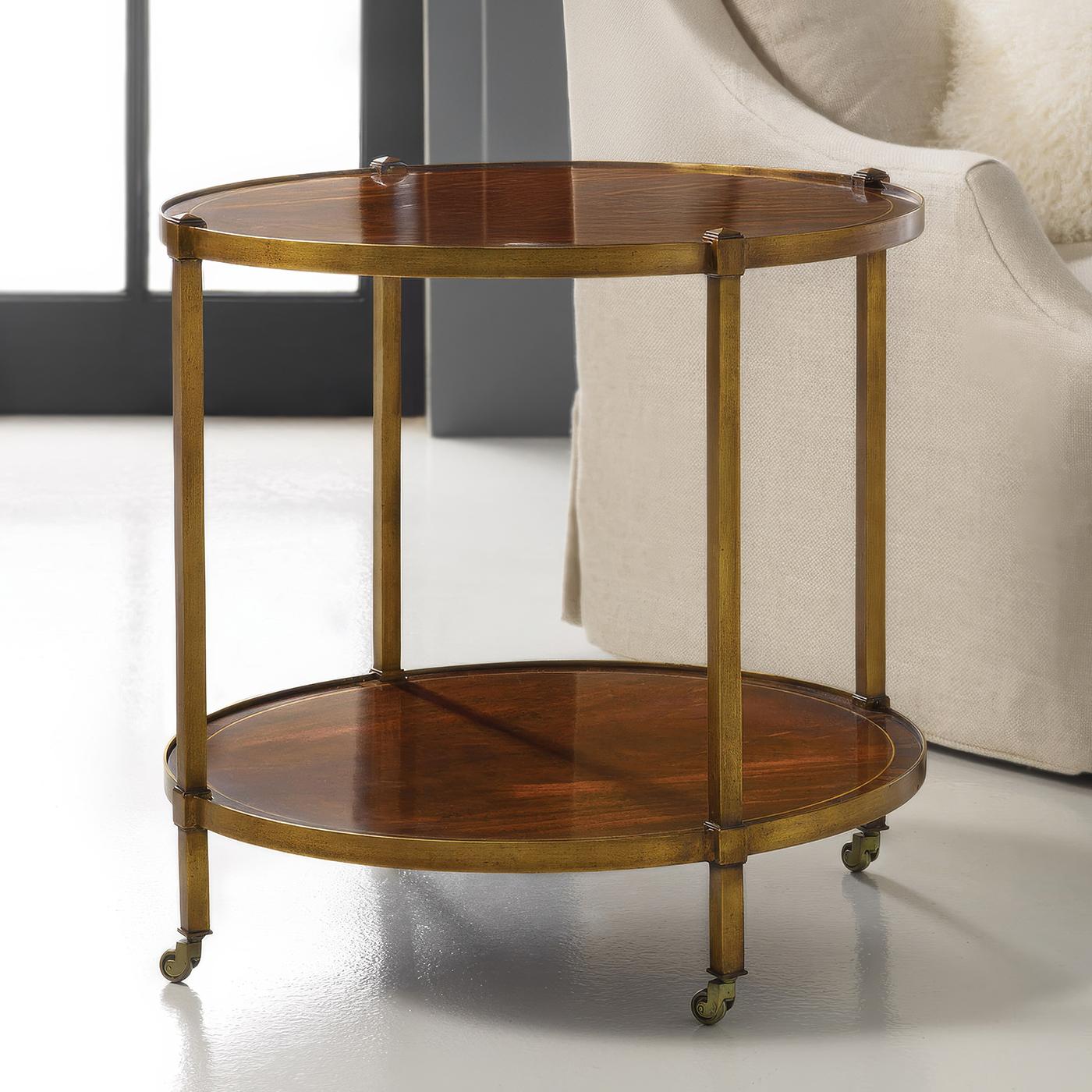 Doté d'un cadre en laiton à deux niveaux, ce meuble exsude une élégance discrète tout en servant de pièce fonctionnelle pour votre maison. Plaquée d'acajou à bandes croisées et incrustée, la table repose sur des pieds classiques à roulettes en