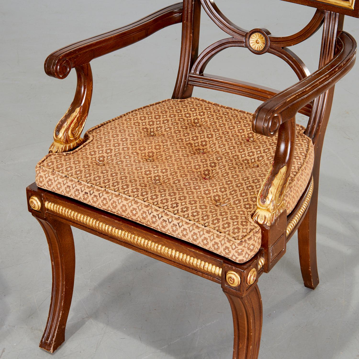 20th c., Regency style armchair, with gilt folate design, medallions and caned seat. The arms terminate in a gold tone folate and carved detail. There is a nice button tufted loose seat cushion. The sabre legs support a caned seat with richly
