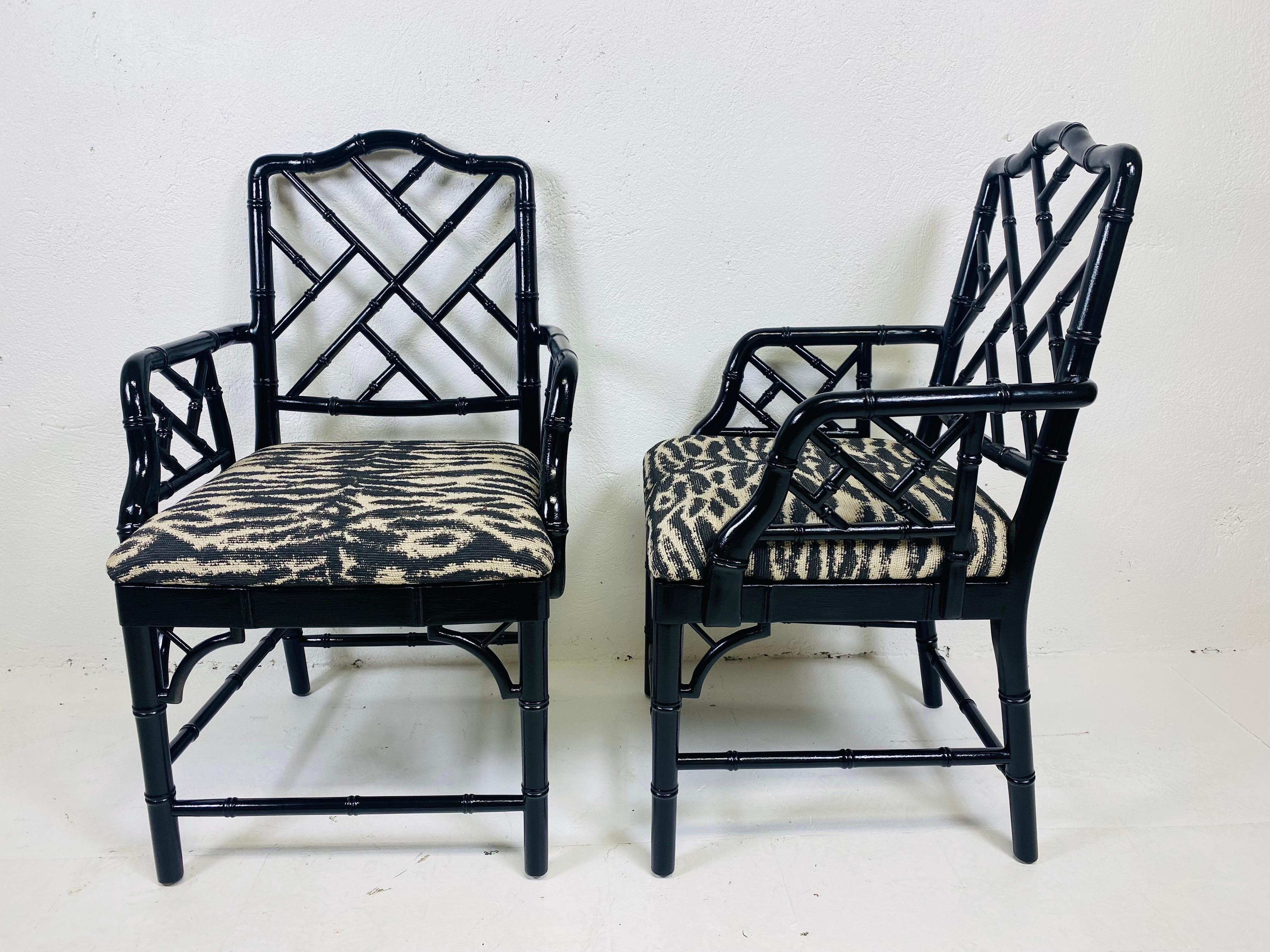 This is a pair of regency inspired faux bamboo black Lacquered arm chairs. These faux bamboo arm chairs have been lacquered with a glossy black and newly upholstered and a tiger pattern fabric.