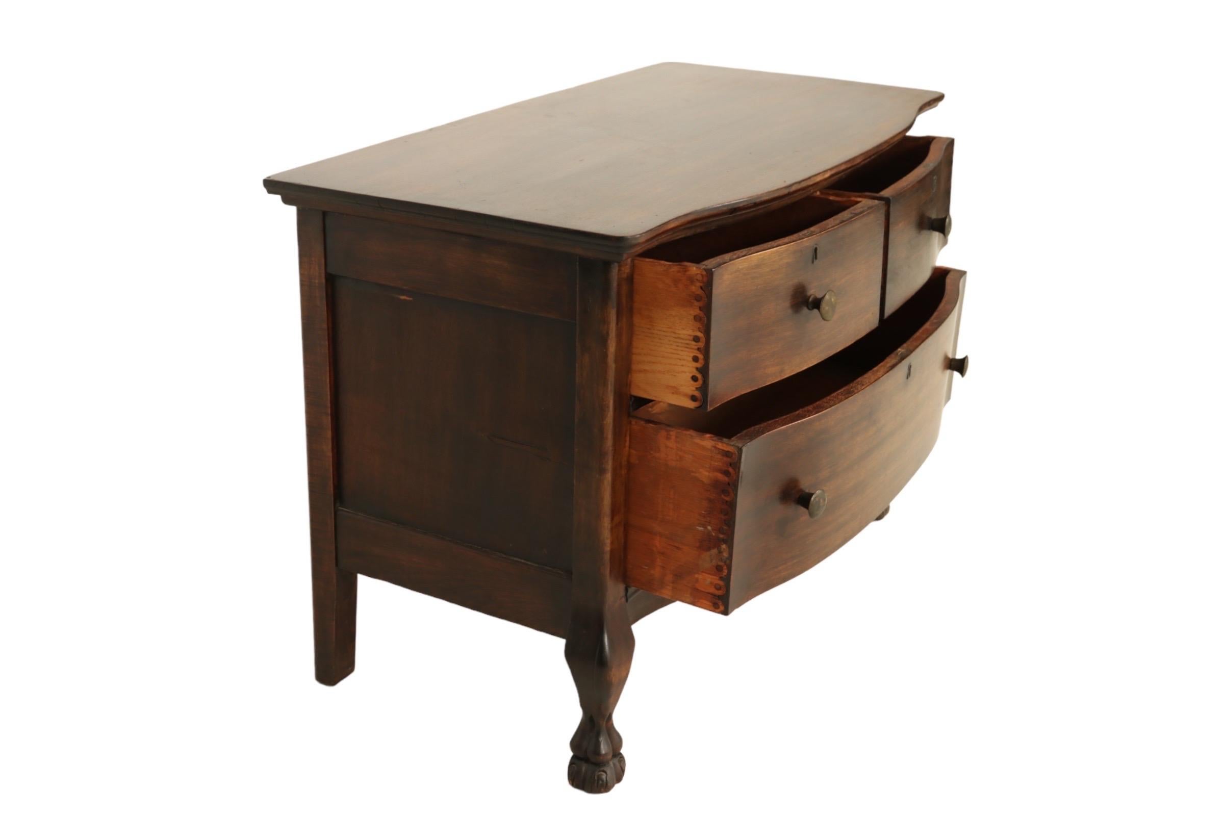 A regency style three drawer low dresser with a restrained bowed front. Drawers with pin and scallop joinery open with round metal knob handles. Below, short cabriole legs finish in paw feet.
 