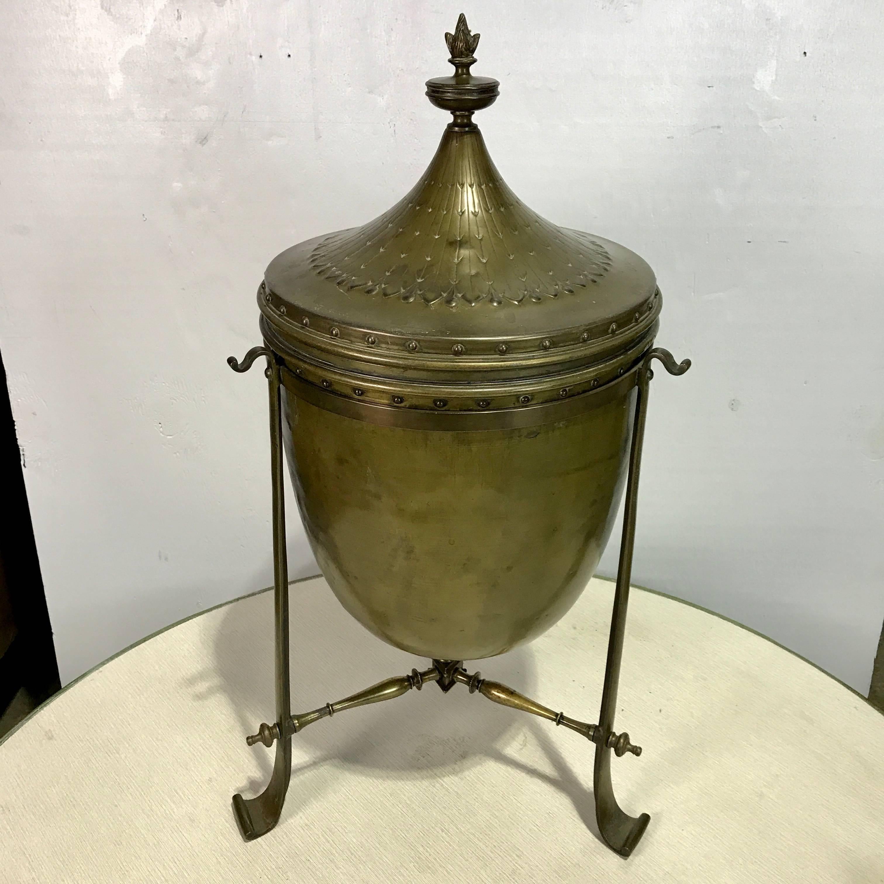 Regency style bronze tinder urn or coal scuttle , of circular form, with removable lid, revealing a black painted tin liner, resting in a bullet shaped cistern, supported by reuleaux triangle bronze base. 
Interior measures 12.5
