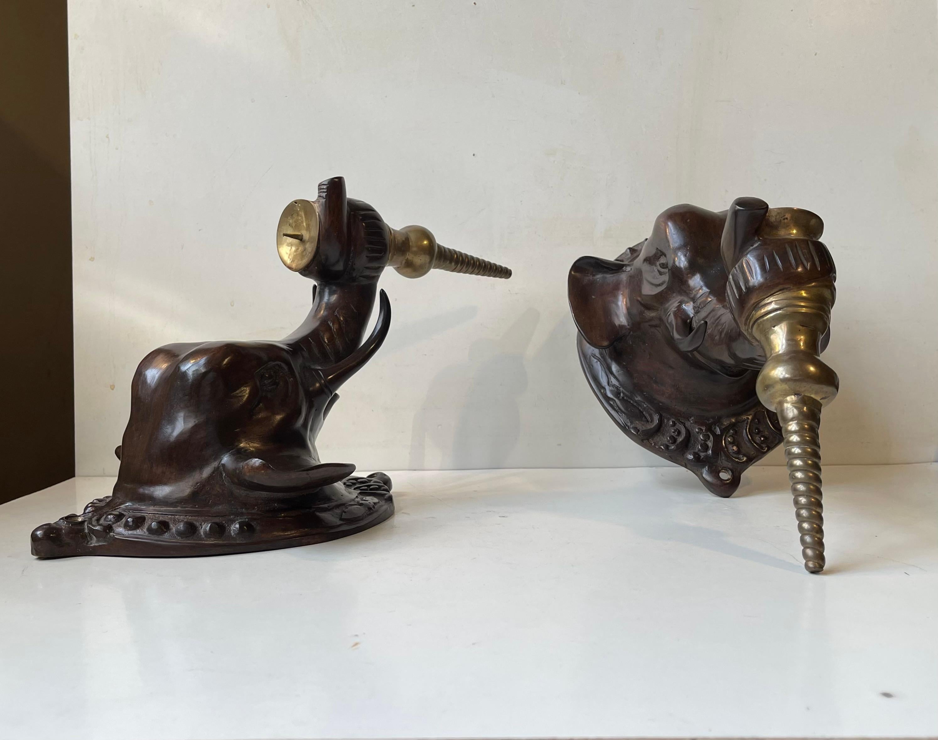 Coppia di candele a elefante in bronzo fuso. Stile Regency con un pizzico di fauna coloniale. Ogni testa di elefante ha un portacandele in bronzo dorato ritorto sospeso alla sua proboscide. Utilizzali con candele grandi da chiesa, a sfera o a