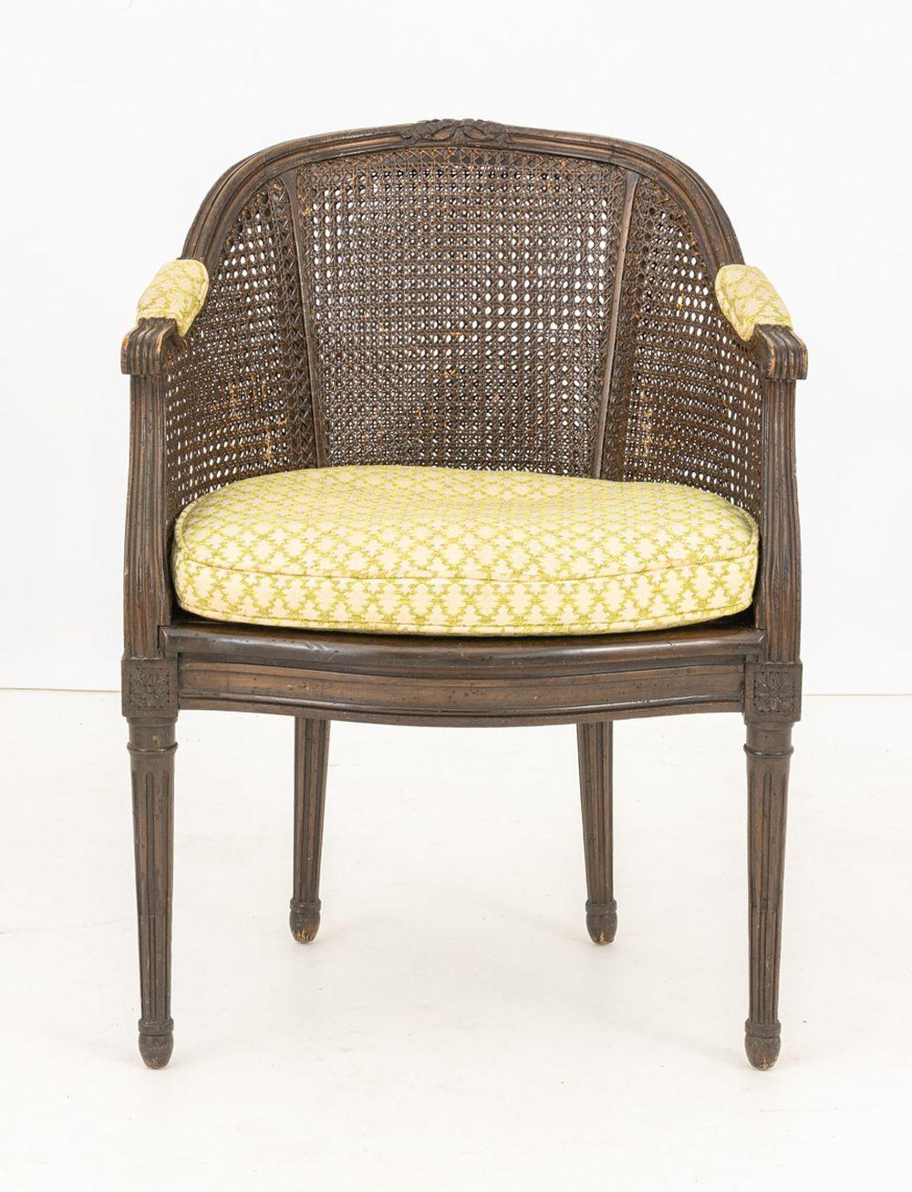 Regency Style Cane-Paneled Barrel Back Bergere, brown painted frame with bow crest, green and white cushion and upholstered arm rests on four fluted tapered legs. 33