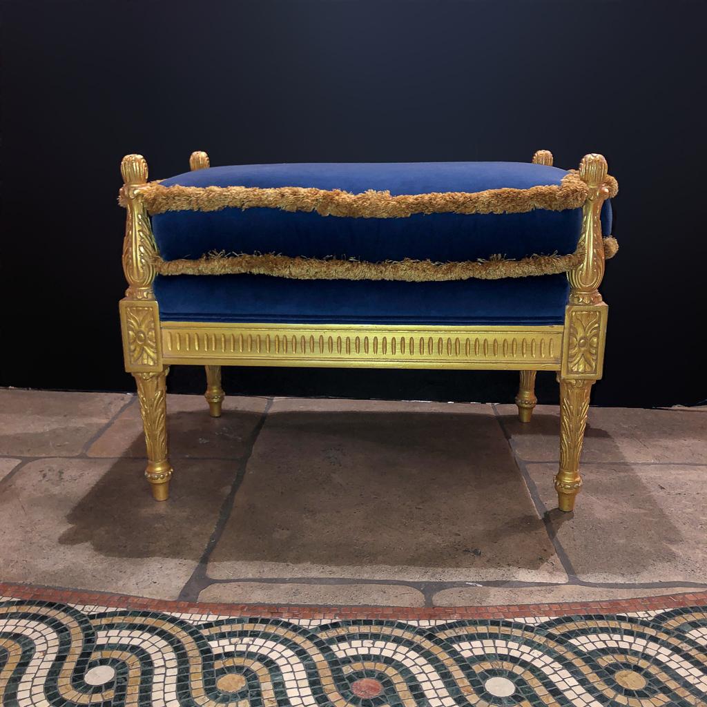 Regency style carved giltwood bench with cobalt velvet upholstery with acanthus carved supports and fluted aprobs.