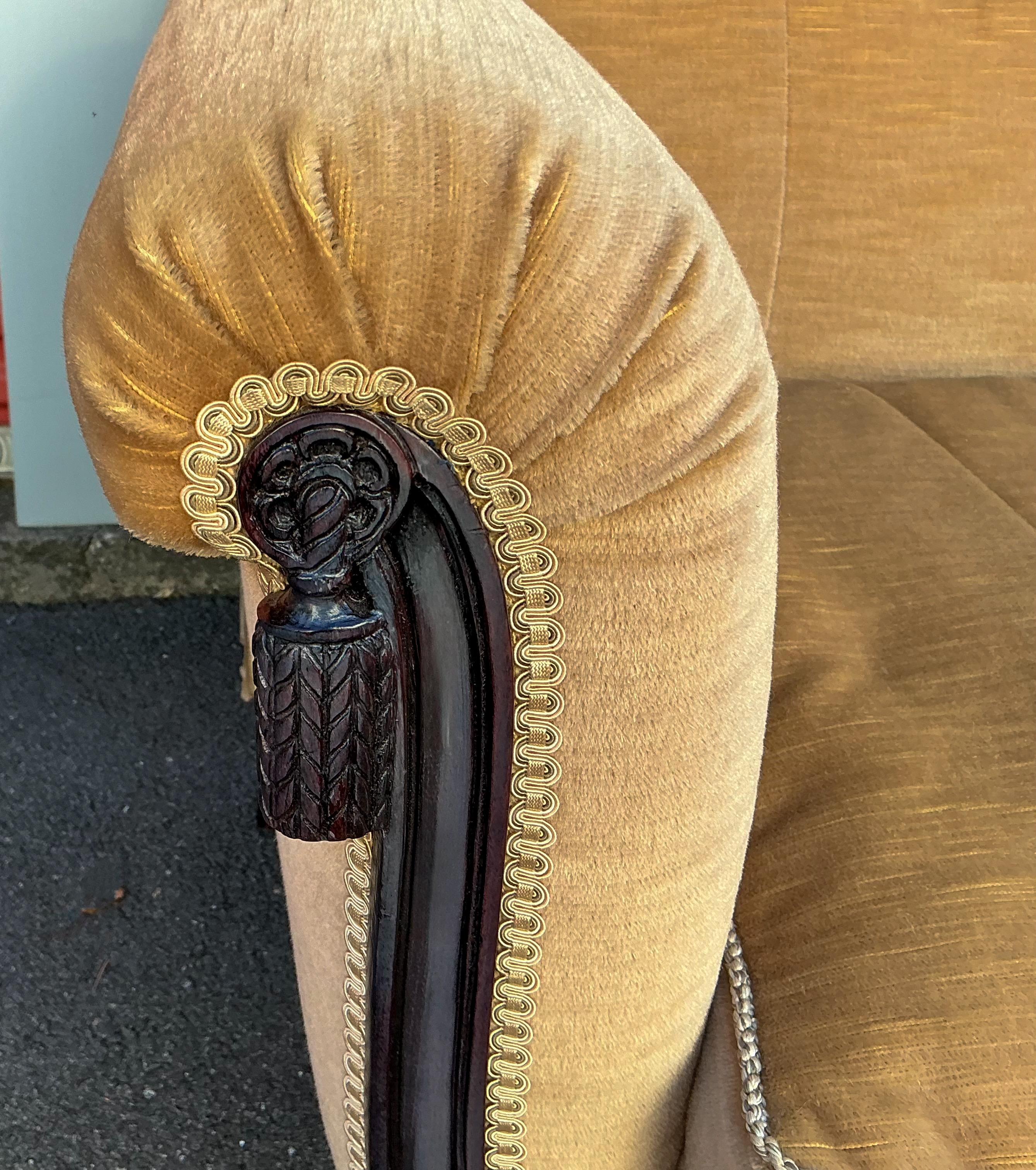 This is a 1950s regency style carved mahogany sofa upholstered in a camel mohair. The arms have a scrolled carved tassel motif. The cushion is down. The camel mohair is in very good condition. 

Shipping is running two to five weeks. For any