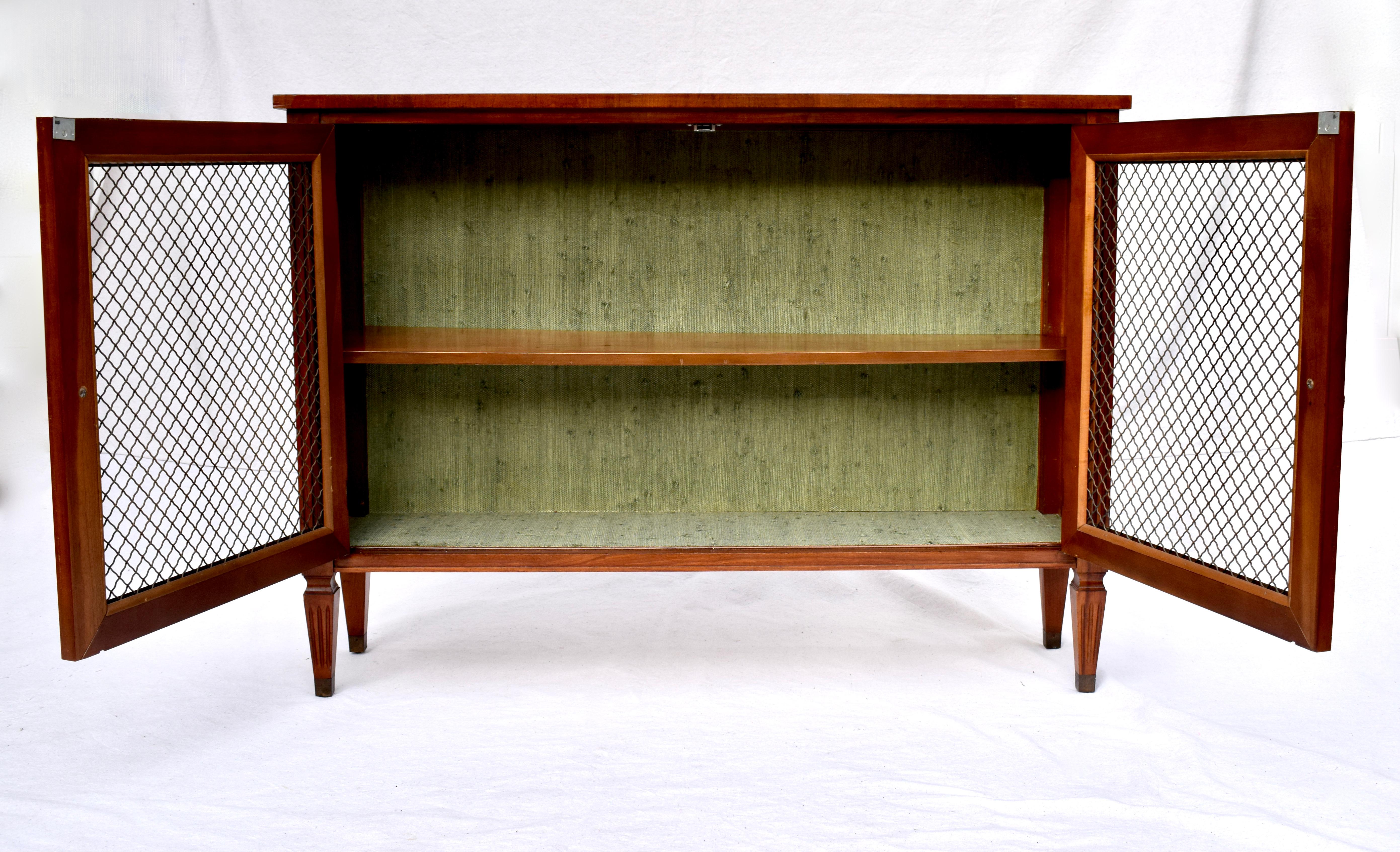 Early 20th c. Regency style walnut & mahogany display cabinet featuring Harlequin inlay top single loose adjustable shelf with two brass grill panel doors & green grasscloth lined interior. Original fully detailed finish with brass capped feet