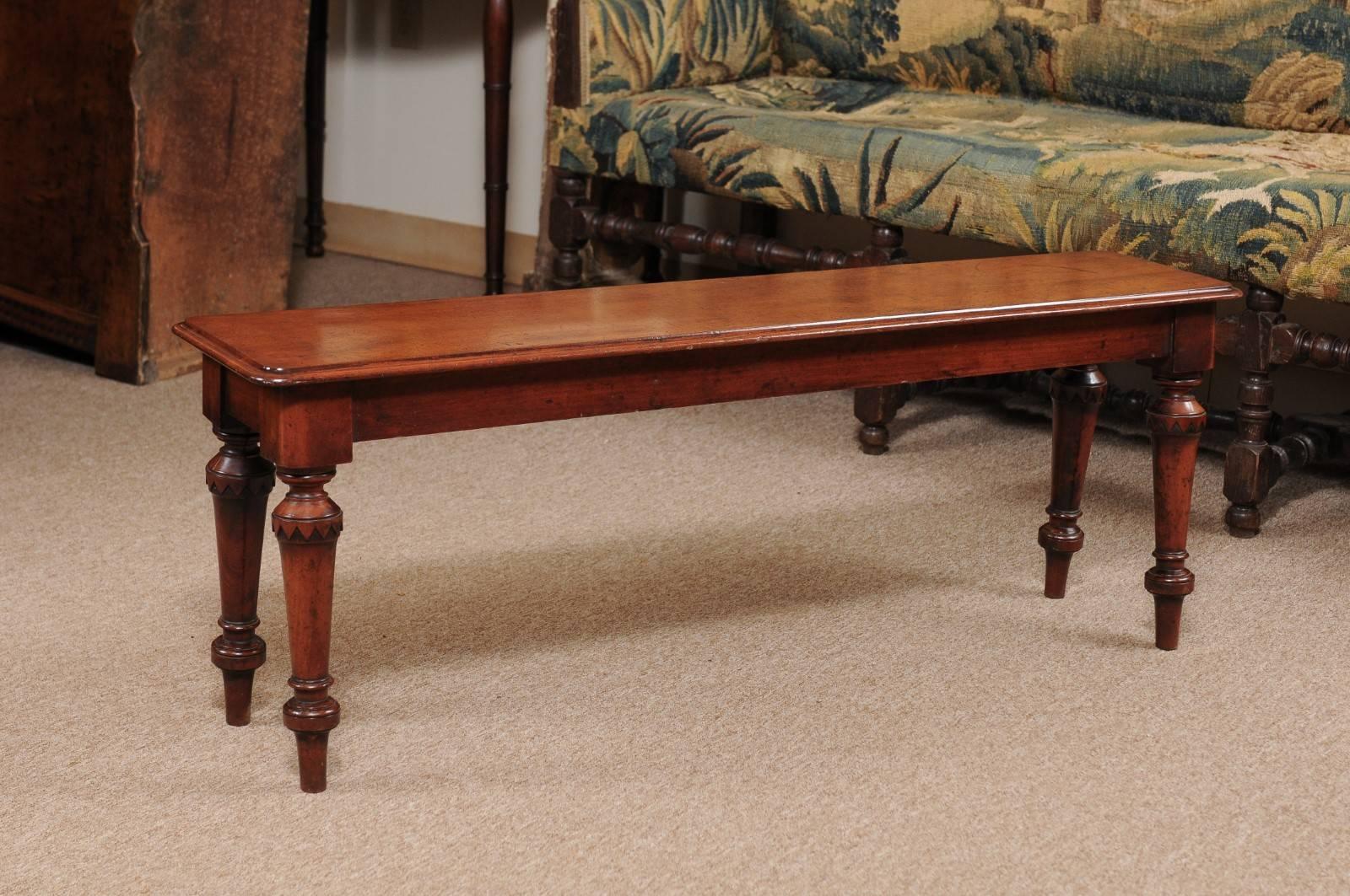 The hall bench constructed out of mahogany with shallow rectangular top and turned splayed legs.
 
    