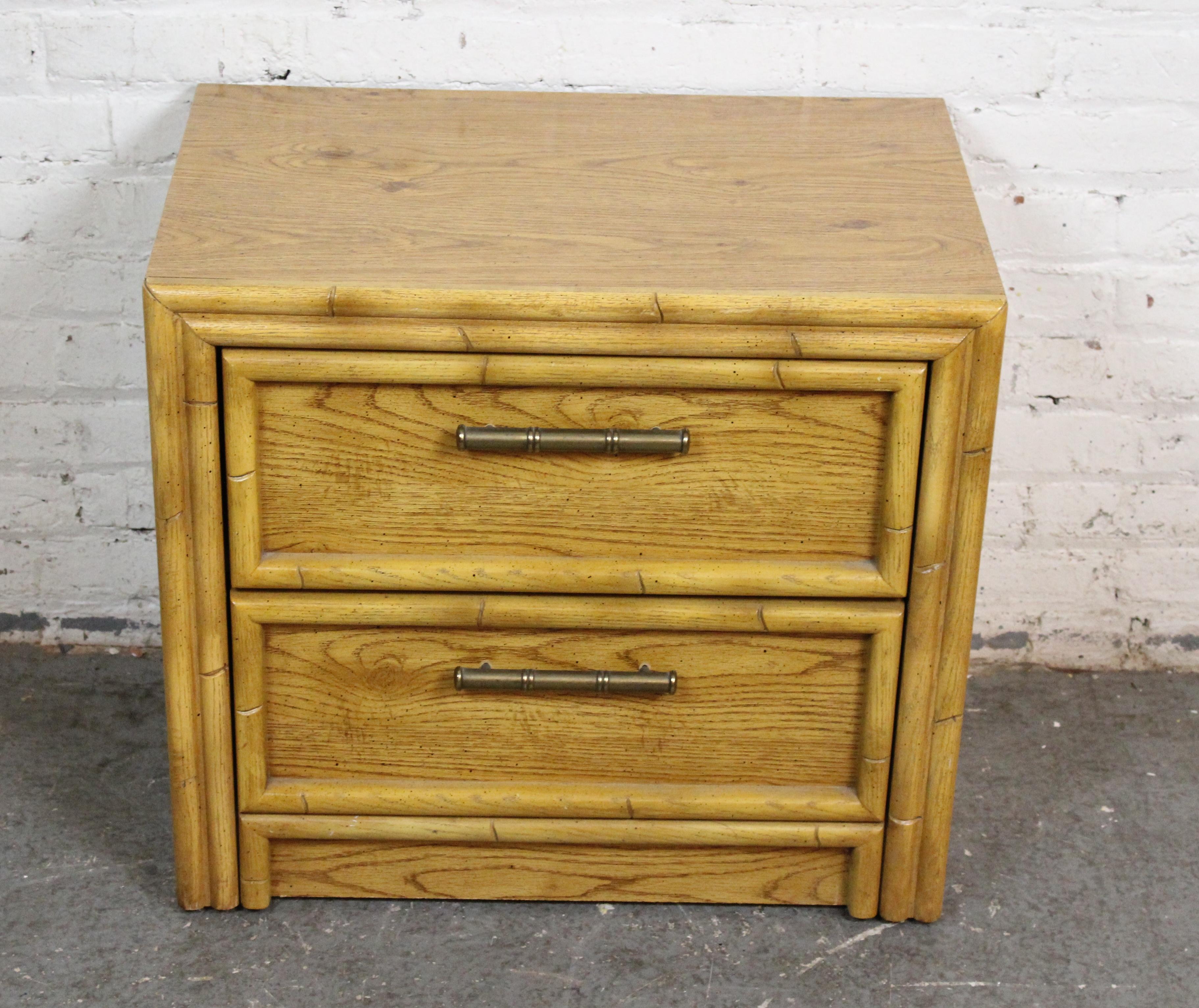 This Hollywood Regency style nightstand adds a pop to your living or bedroom, with bright oak coloring and brass hardware. Two drawers, bamboo styling, made by Lea Furniture. Used as a bedside table or plant stand.
Please confirm location NY or NJ