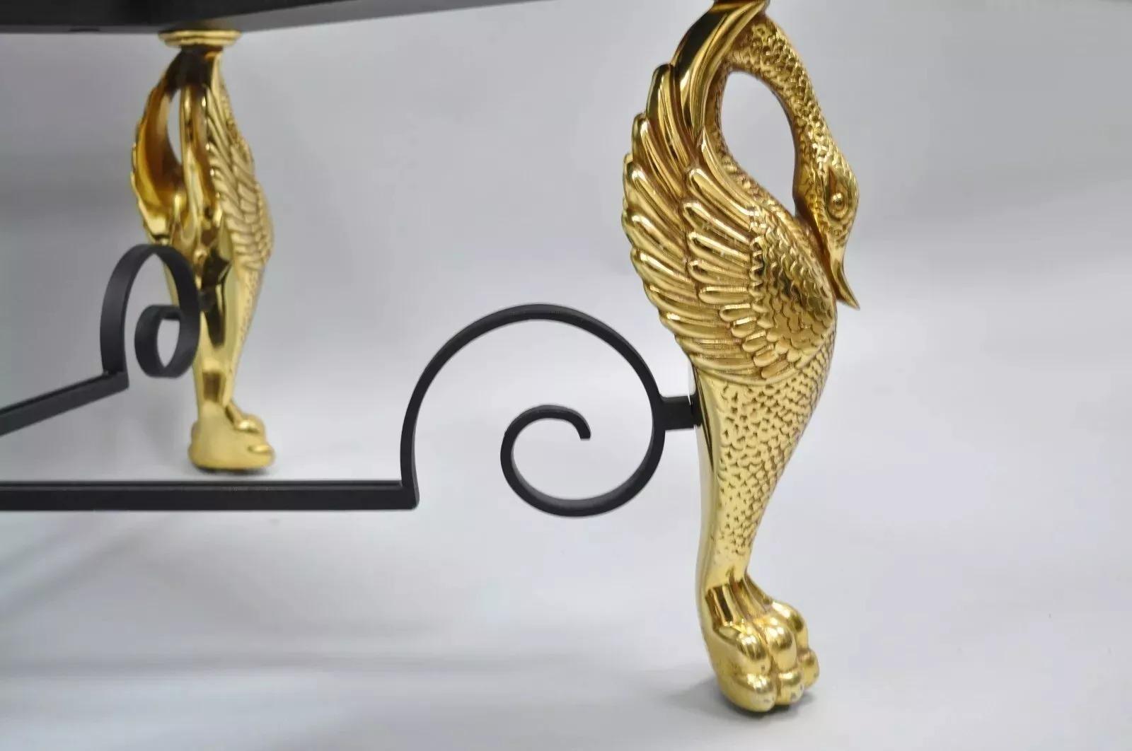 Tavolino da caffè rettangolare in ferro e vetro dorato con base a cigno figurato in stile Regency (A). L'articolo presenta una struttura in metallo e ferro, un piano in vetro con bordo smussato, gambe a cigno dorate, un terminale a sfera in ottone,