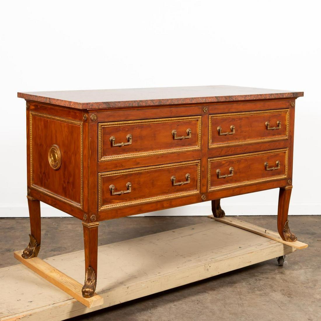 Contemporary. Parcel gilt burl wood veneered commode or chest in the regency taste, having a red marble top, corner rosettes, the four-drawers and sides with rais-de-coeur detail, and rising on tapering curved legs with dolphin-form sabots. CPI