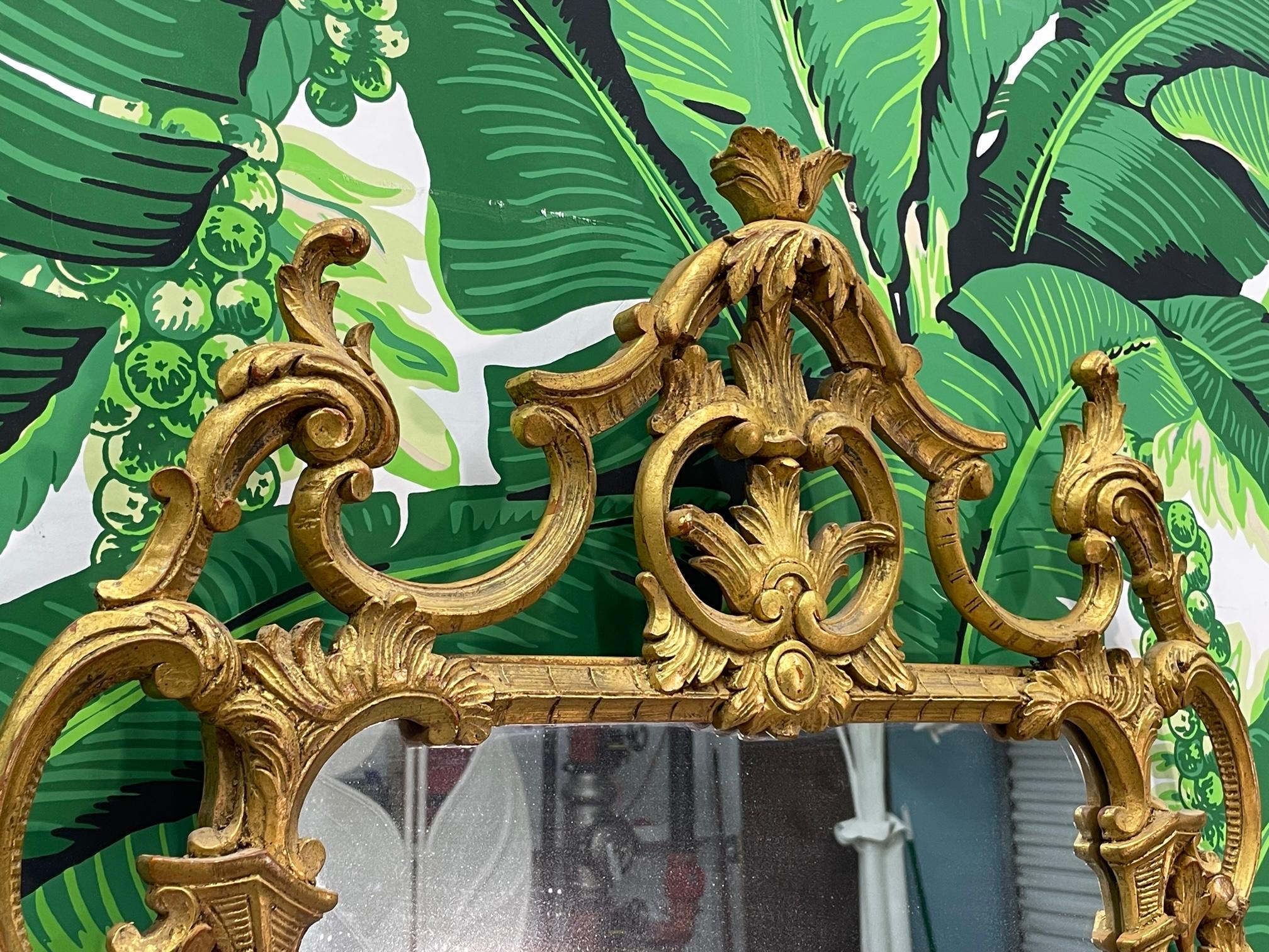 Hand carved midcentury wall mirror features and ornate pierced frame of acanthus leaves and columns and a gold gilded finish. Good condition with minor imperfections consistent with age, see photos for condition details.



