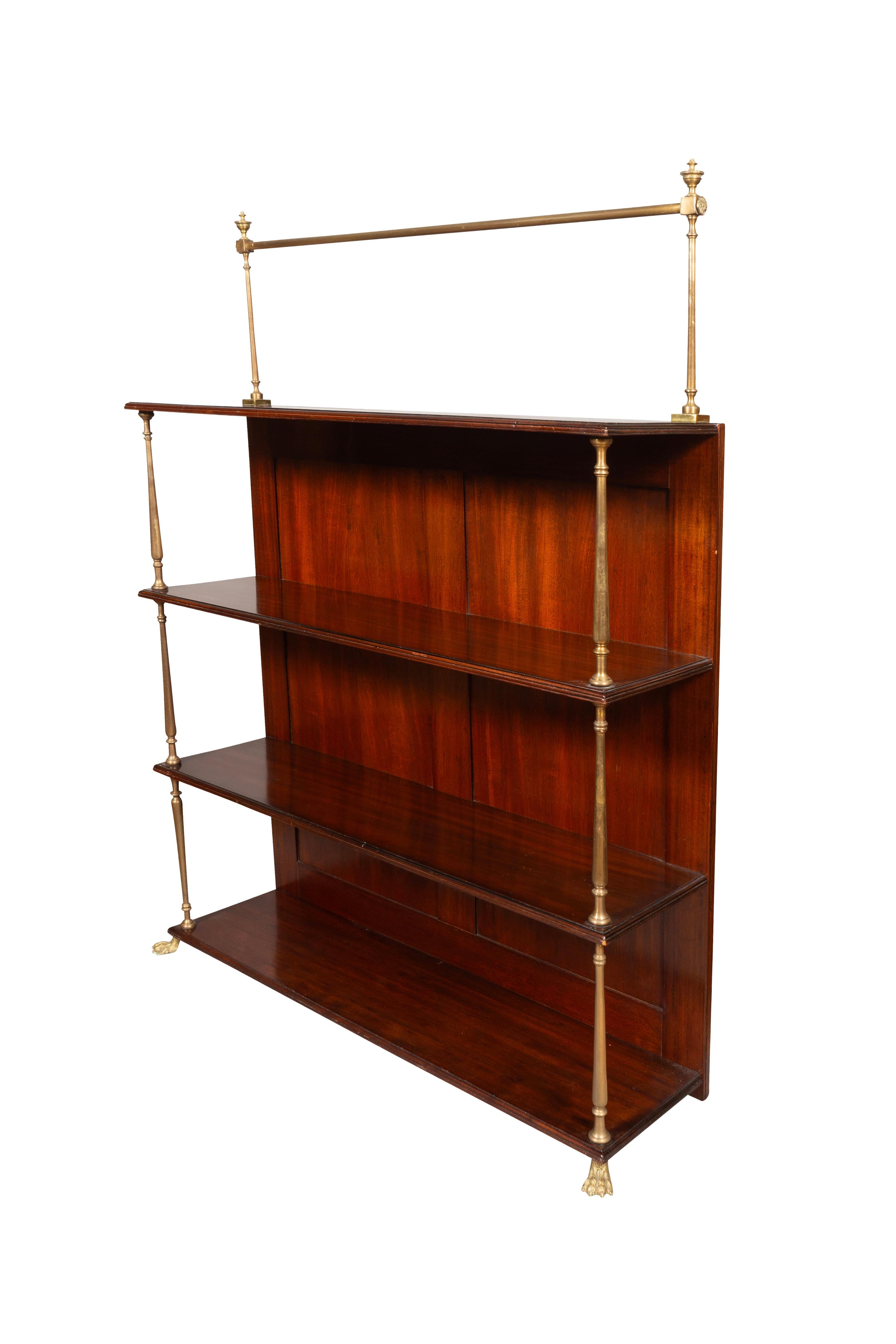 With a top brass rail over a rectangular top over three shelves with turned brass dividers, brass paw feet.
