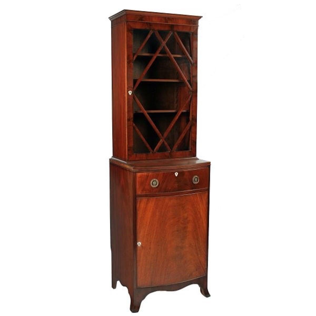A Regency style early 20th century mahogany bookcase.

The bookcase comprises of a glazed upper section and a bowfronted cupboard lower section.

The upper glazed section has slim astragals at angles across the glass and on the door frame a