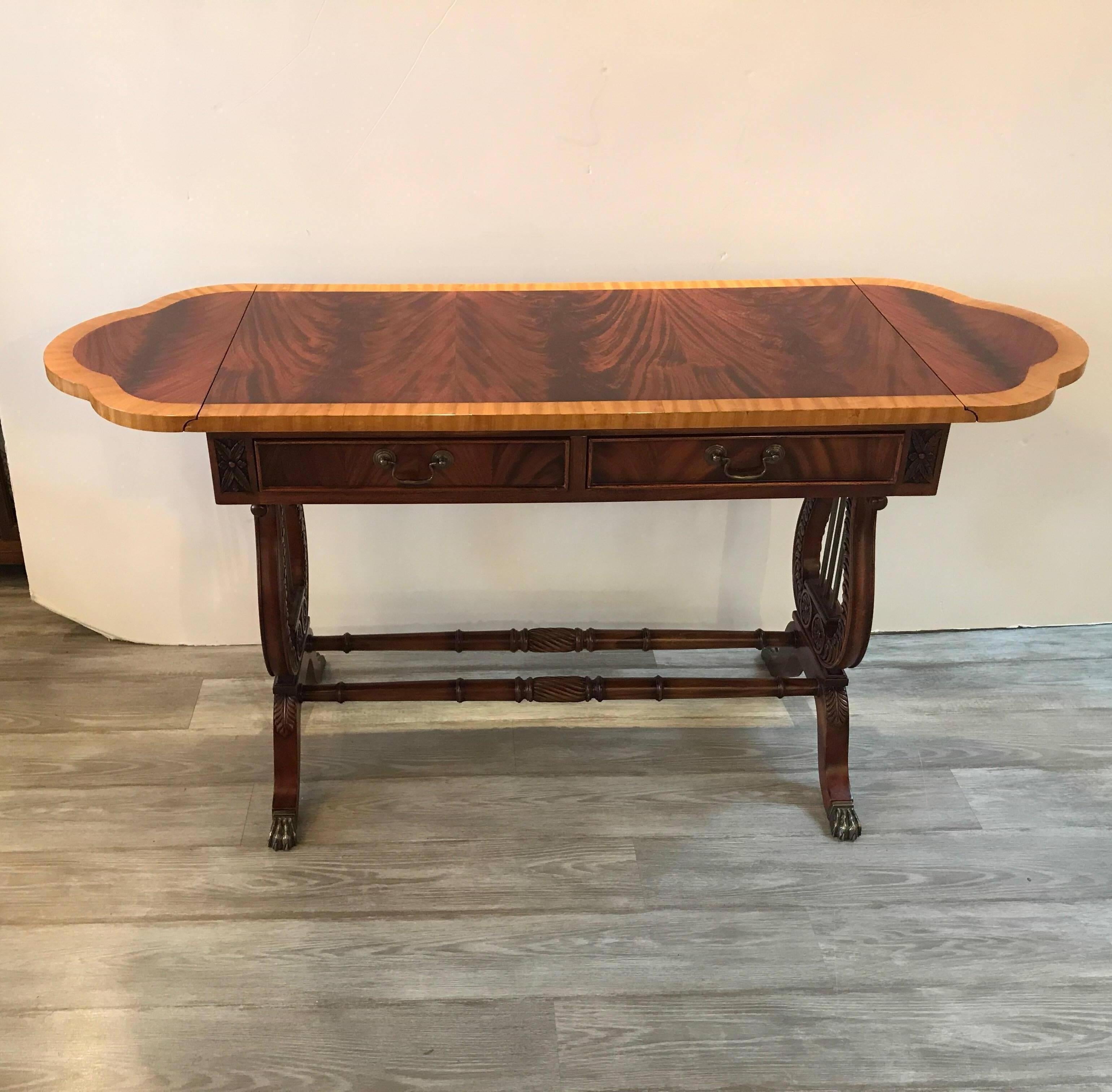 Elegant flame mahogany and satinwood console sofa table with drawers. The figurative top with drop leaf sides with two small drawers below. The base with carved lyre shaped sides and stretcher base. The piece is 40 inches wide with a 10.5 inch leaf