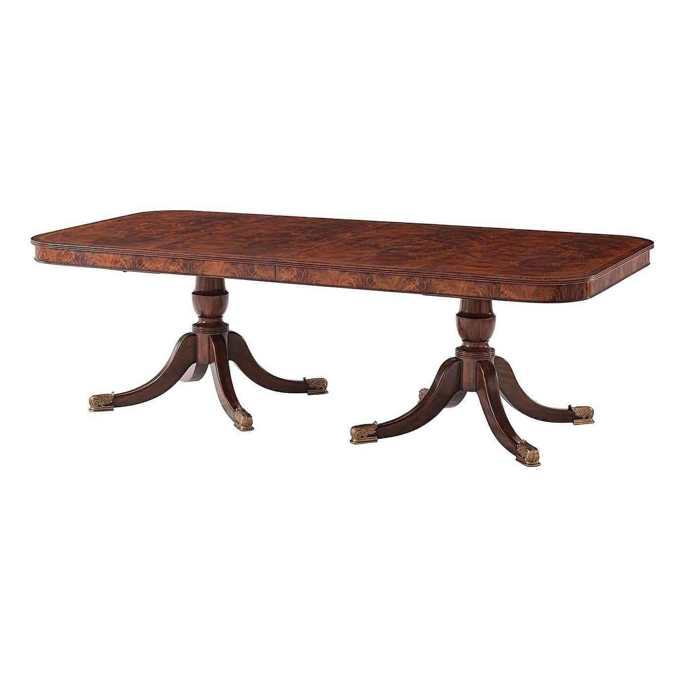 A fine Regency style mahogany and flame veneered extending dining table, the rectangular reeded edge top with rounded corners crossbanded in chestnut burl and morado, with two additional self storing leaves, above a mahogany apron, on two baluster