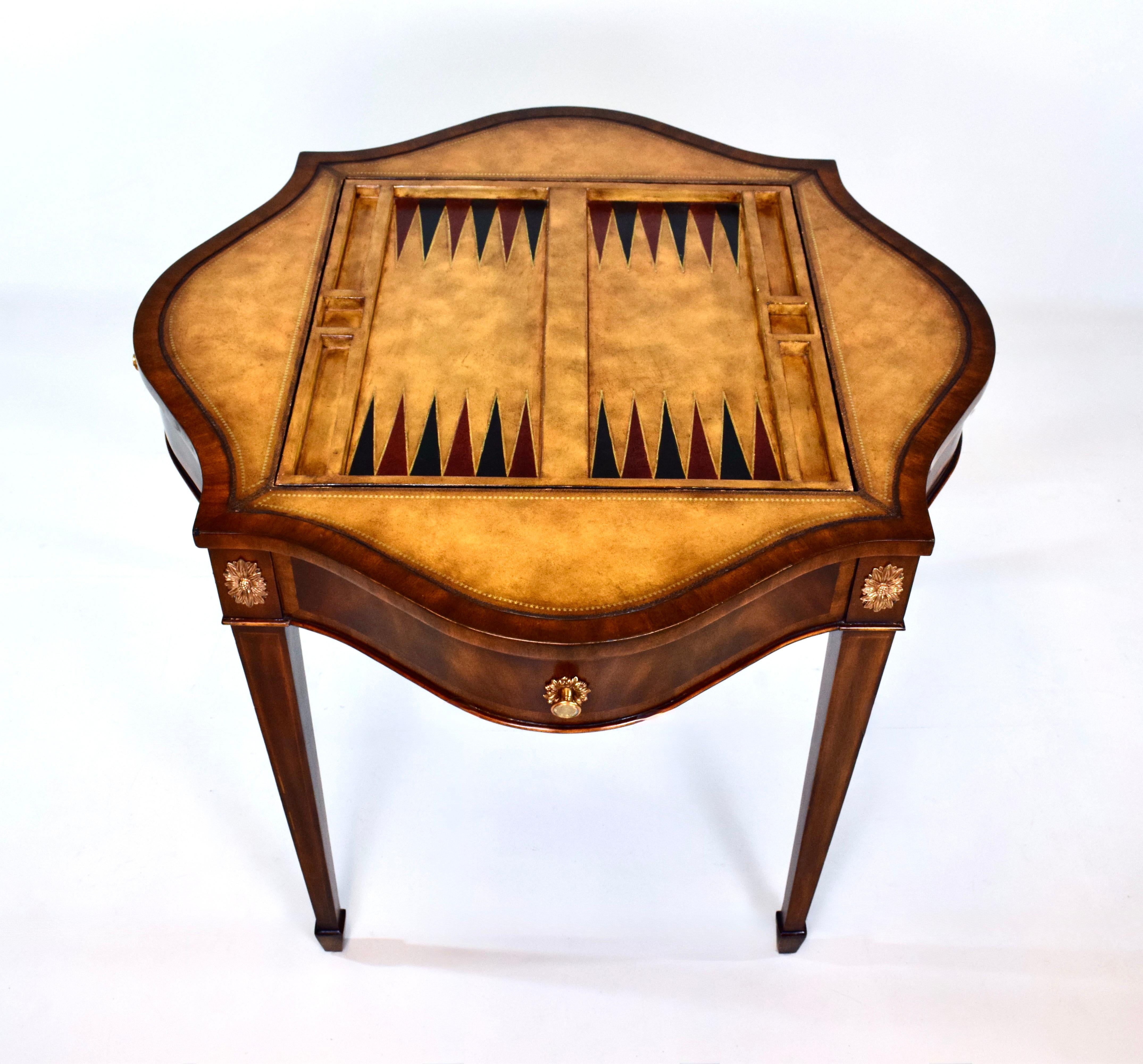 An elegant backgammon/ chess, checkers  or card game table by Maitland Smith in the Regency style with Mahogany banded & tooled leather top, two drawers with flip top insert. The entire table is beautifully embellished with caste brass detailing. 