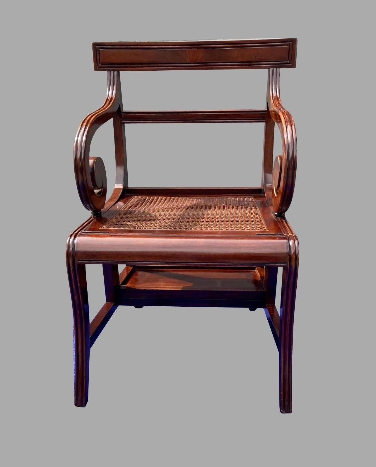 Sedia da biblioteca metamorfica in mogano in stile Regency su modello inglese di Morgan & Sanders. Quando è chiuso, il pezzo è una comoda sedia con sedile a rotelle. Si apre per rivelare 4 gradini foderati in pelle con lavorazione dorata. Si tratta