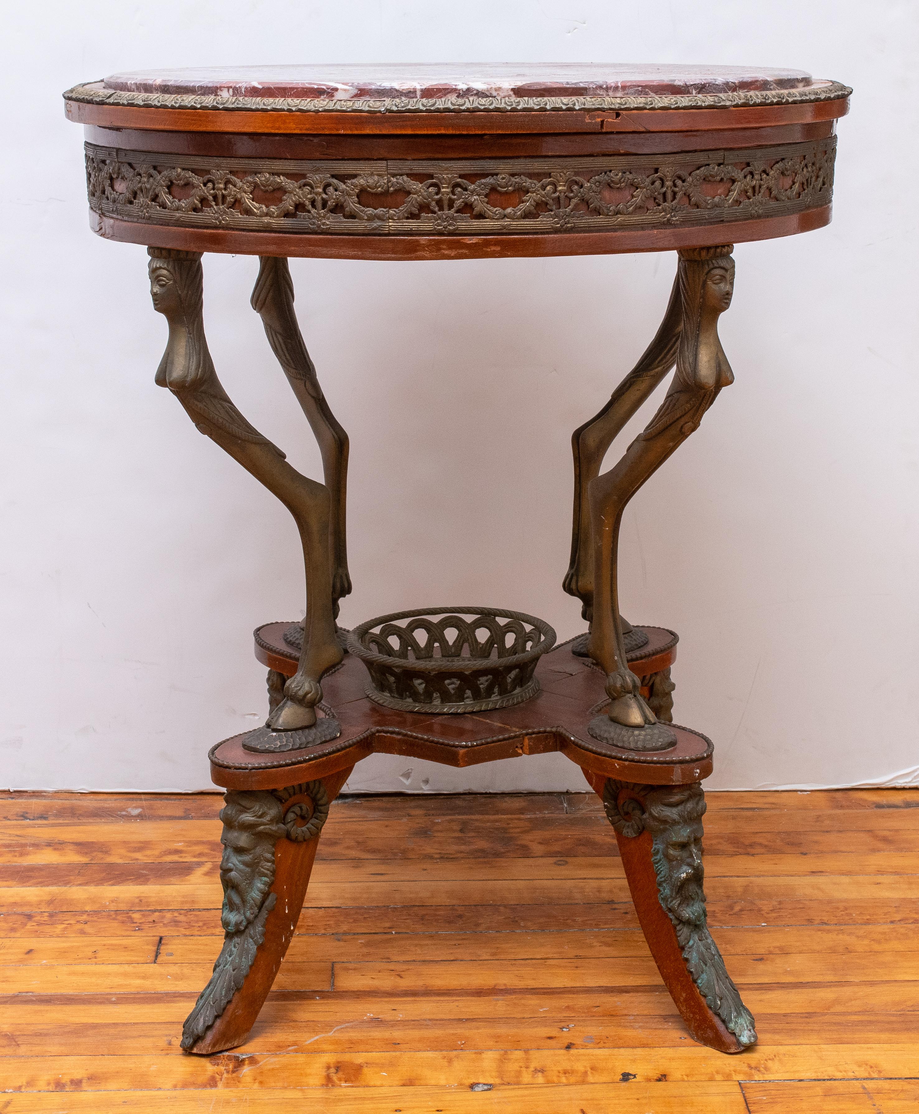 Italian Neoclassical style rosso antico marble-topped circular center table, on a deep apron with scrolling foliate giltmetal mounts, the top supported by four Grecian female monopedae above a quatrefoil shaped gallery on scrolling acanthus feet.