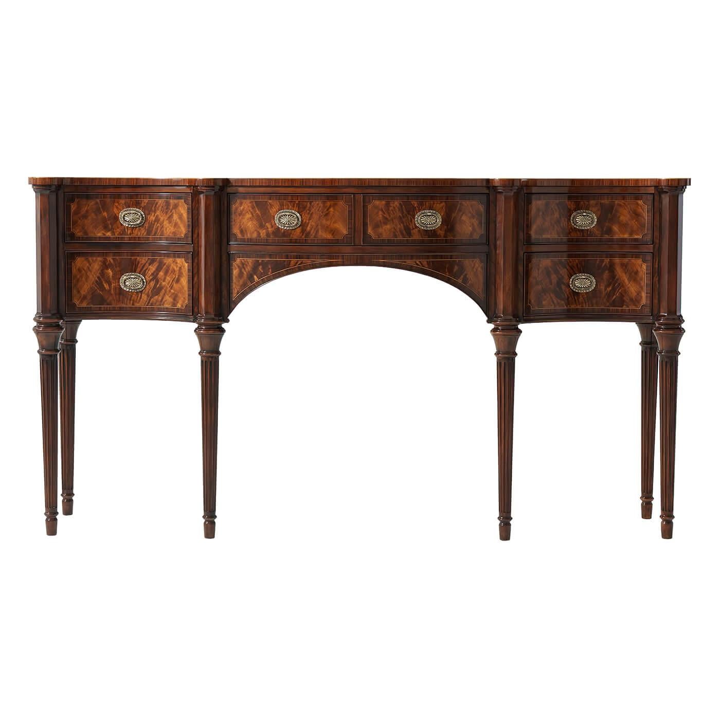 A Regency style mahogany and okum veneered line strung sideboard, the serpentine rosewood crossbanded top with protruding corners above turned uprights and tapering fluted legs, the central double-fronted frieze drawer above an arched apron, flanked