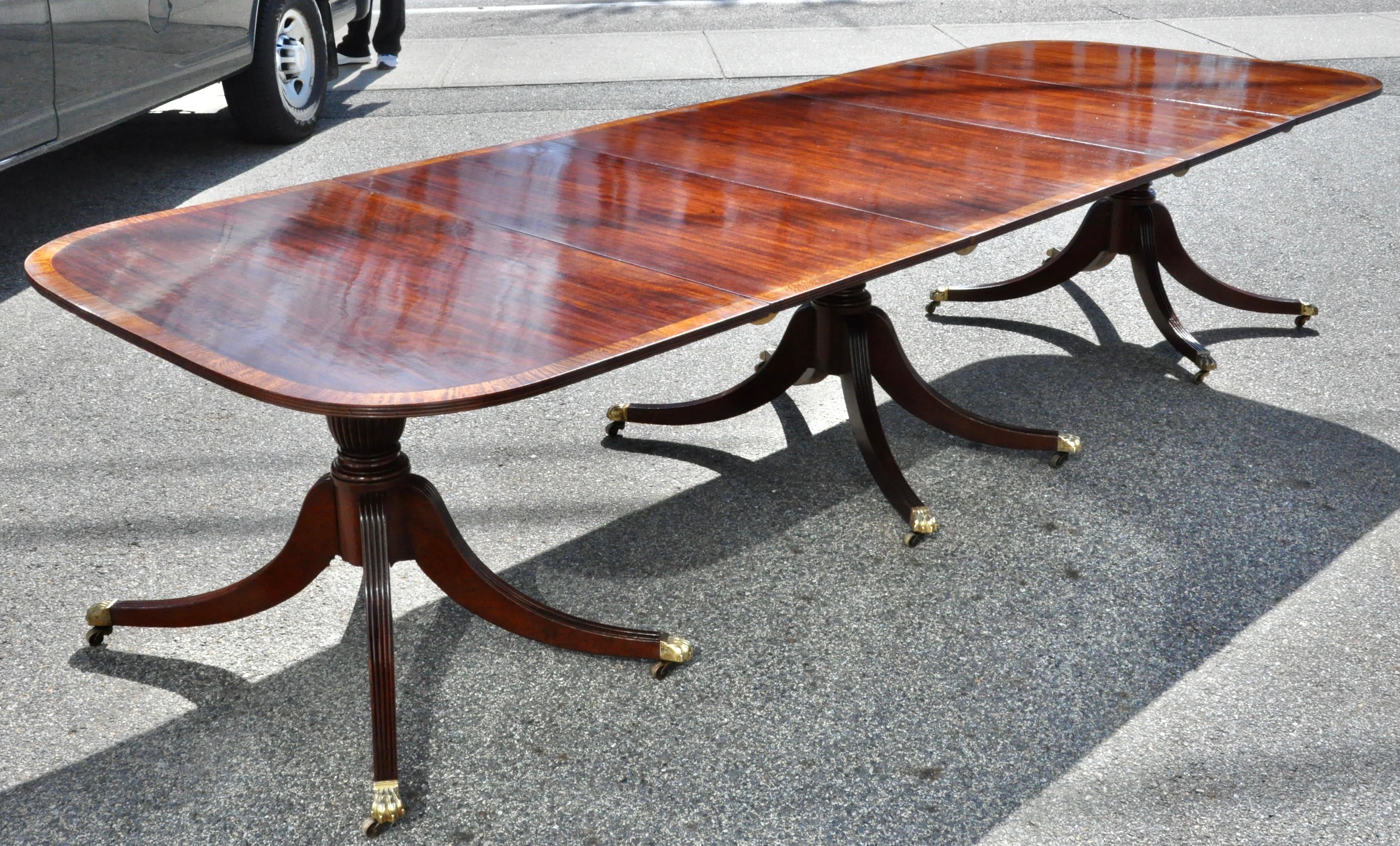 Turn of the century Regency style solid mahogany dining table with satinwood banding. Three sections with two original additional leaves. Very supportive reeded splay leg pedestals. Wonderful figuring and color.

Measures: Fully extended 138